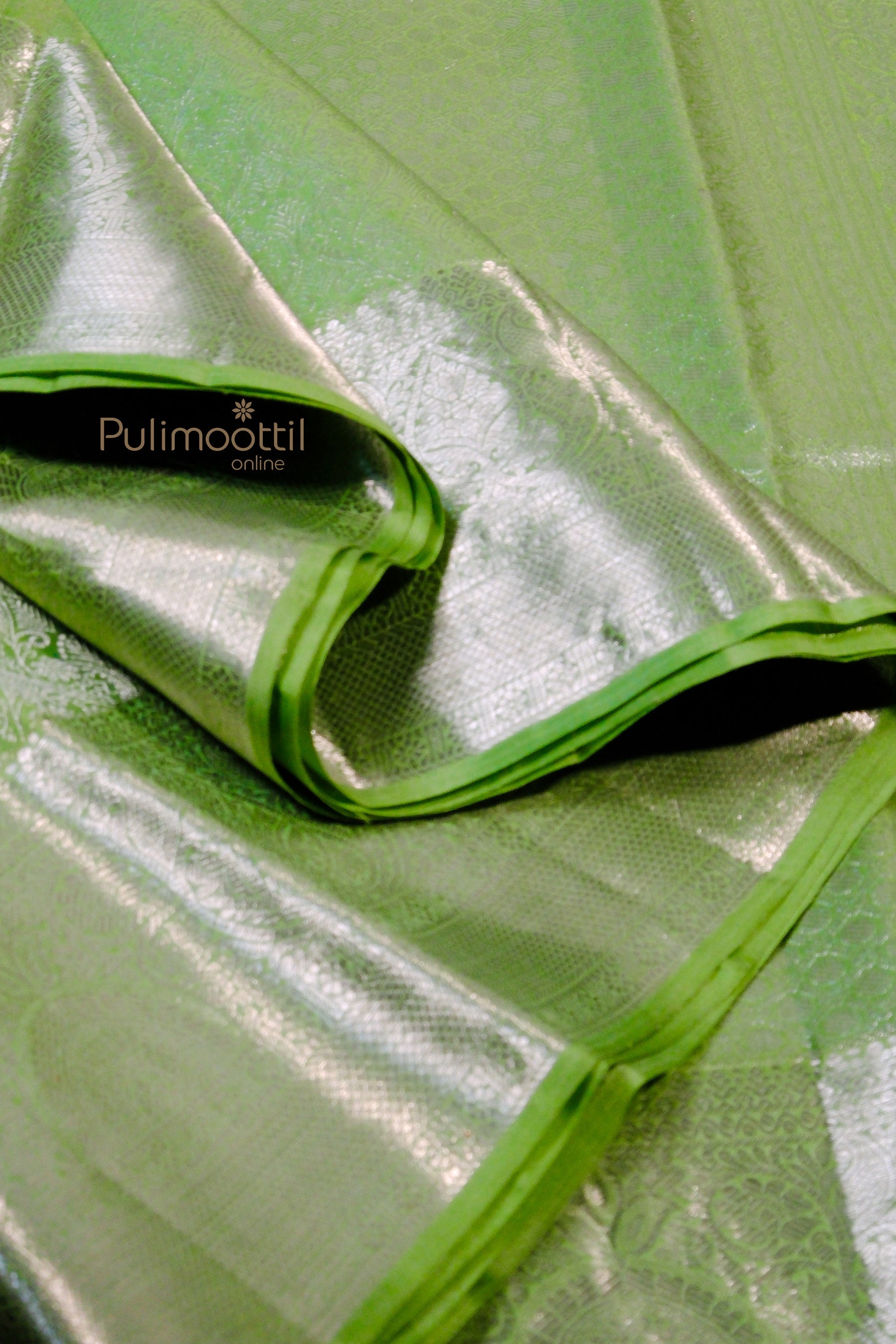 Close-up of pista green Kanchipuram silk saree showcasing silver zari border and fine craftsmanship