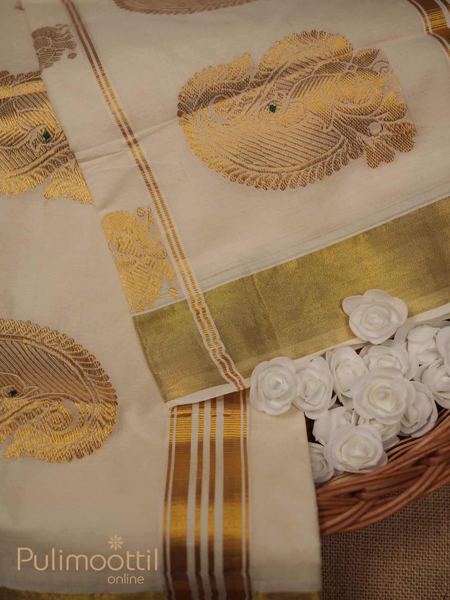 Off‑white Kerala power‑loom saree with golden zari buttas on the body and triple golden‑stripe kasavu‑style border, folded to highlight shimmer.