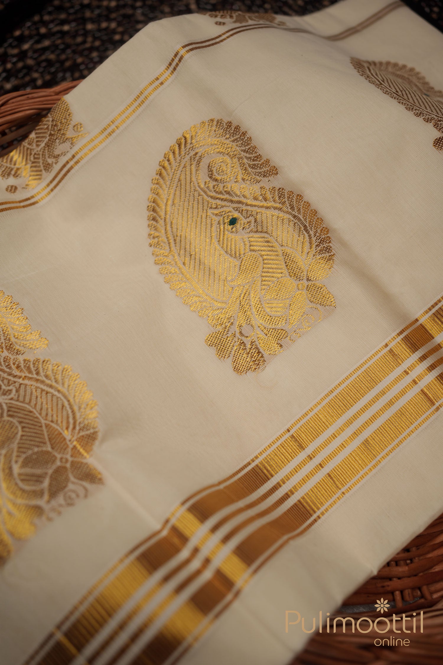 Off-white Kerala power‑loom kasavu saree with golden zari buttas on the body and triple golden-stripe kasavu border, folded to highlight its lustrous texture.