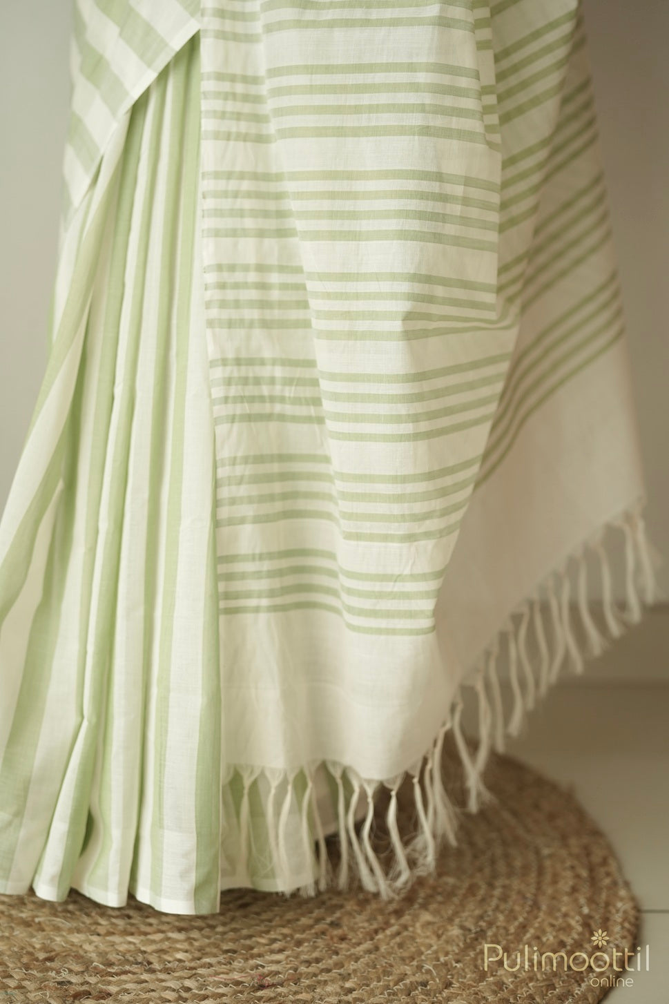Close-up of pastel green and cream pure handloom cotton saree with striped pleats and tassel edging – sarees under 5000.