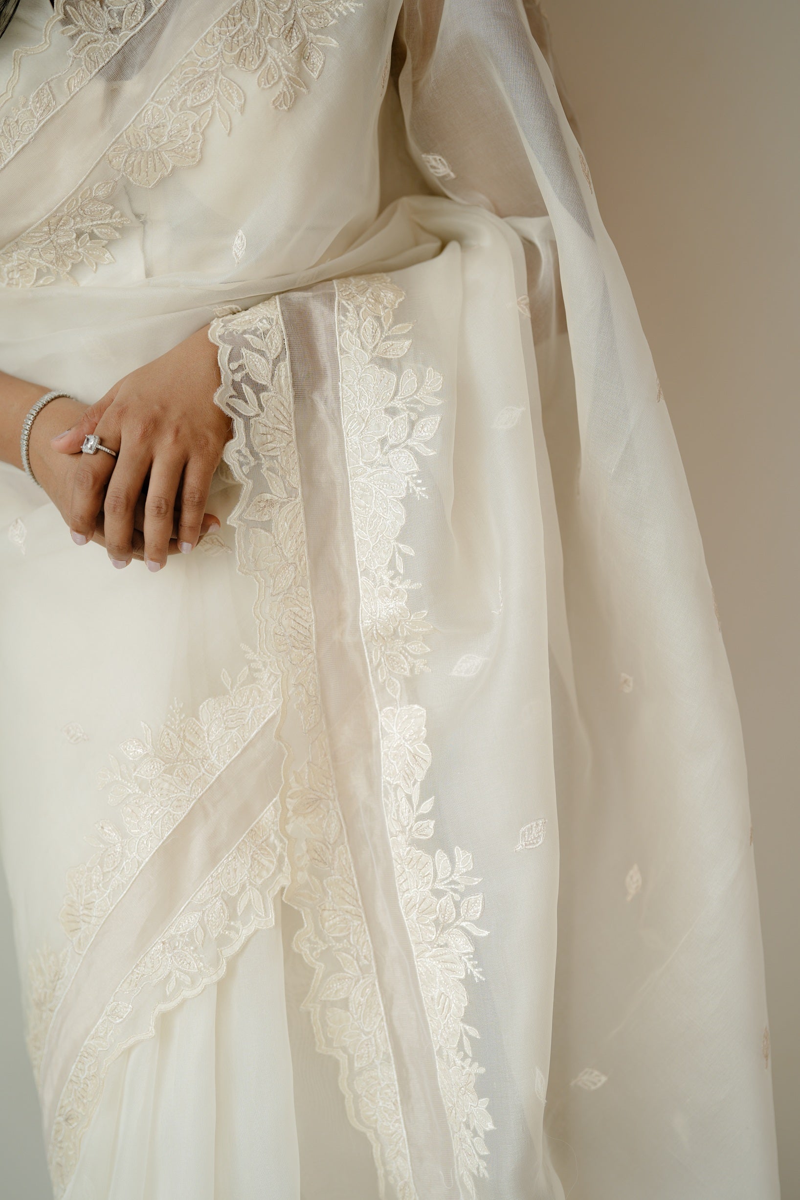 Close-up of the saree’s pallu and lower section, highlighting the elegant floral embroidery and the soft, translucent fabric draping naturally.