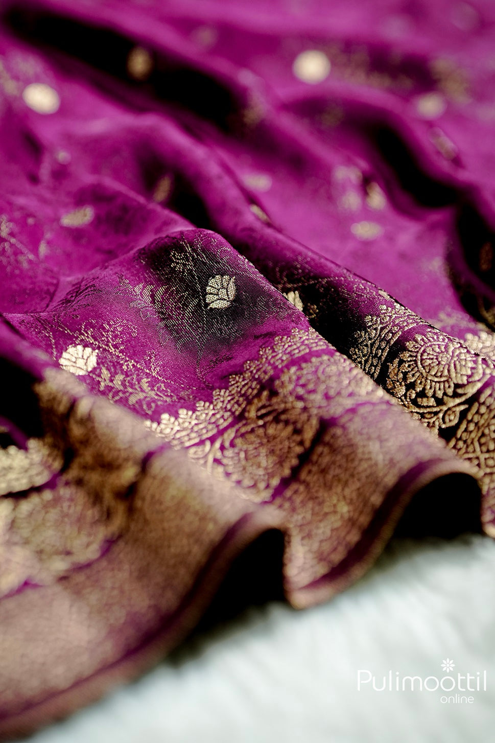 Close-up of purple Uppada Banarasi silk saree with copper zari floral self-design and intricate Banarasi border in gold weaving.