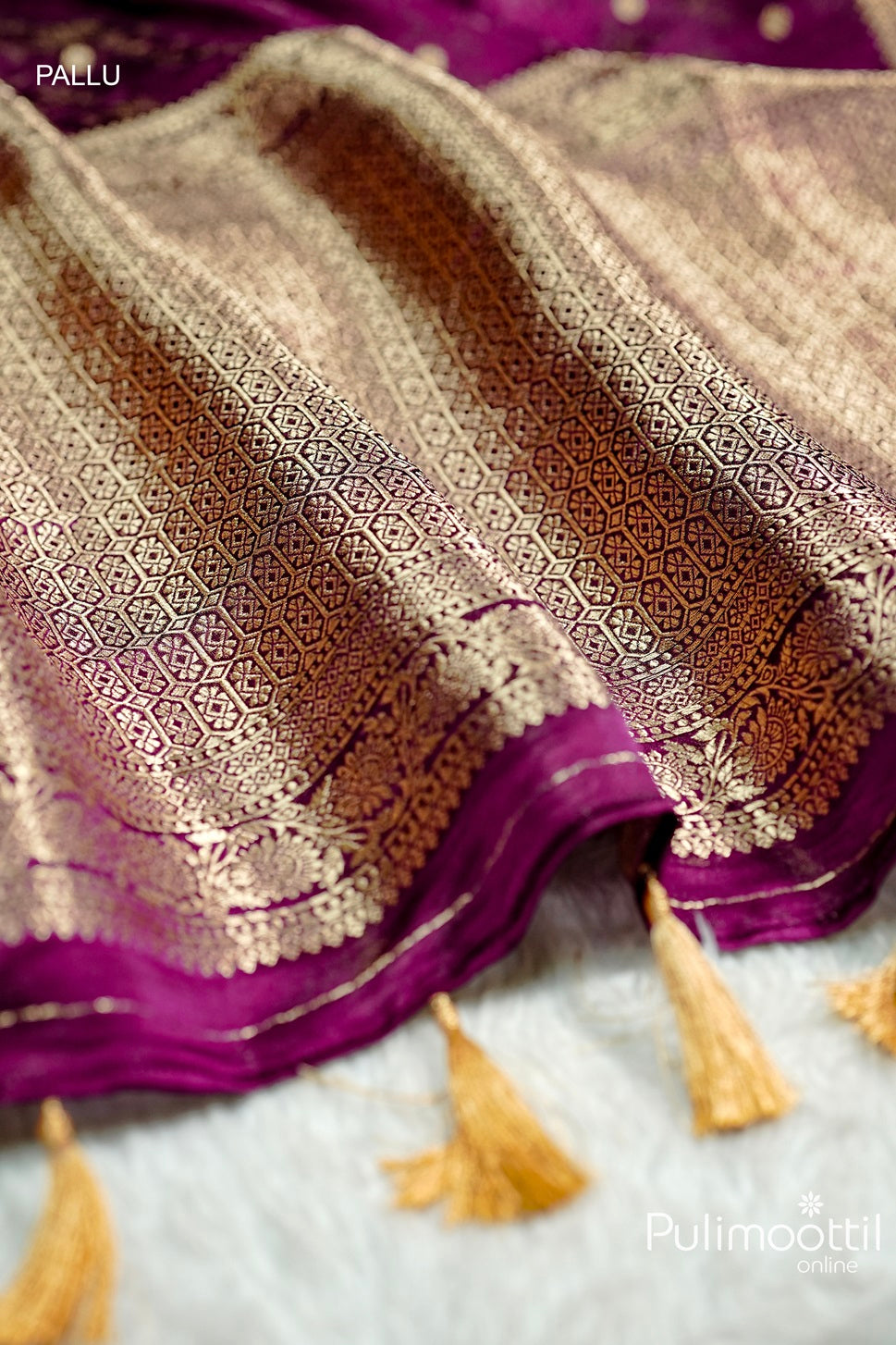 Designer pallu of purple Uppada Banarasi silk saree featuring geometric copper zari weaving, floral motifs, and tasselled edging on rich silk fabric.