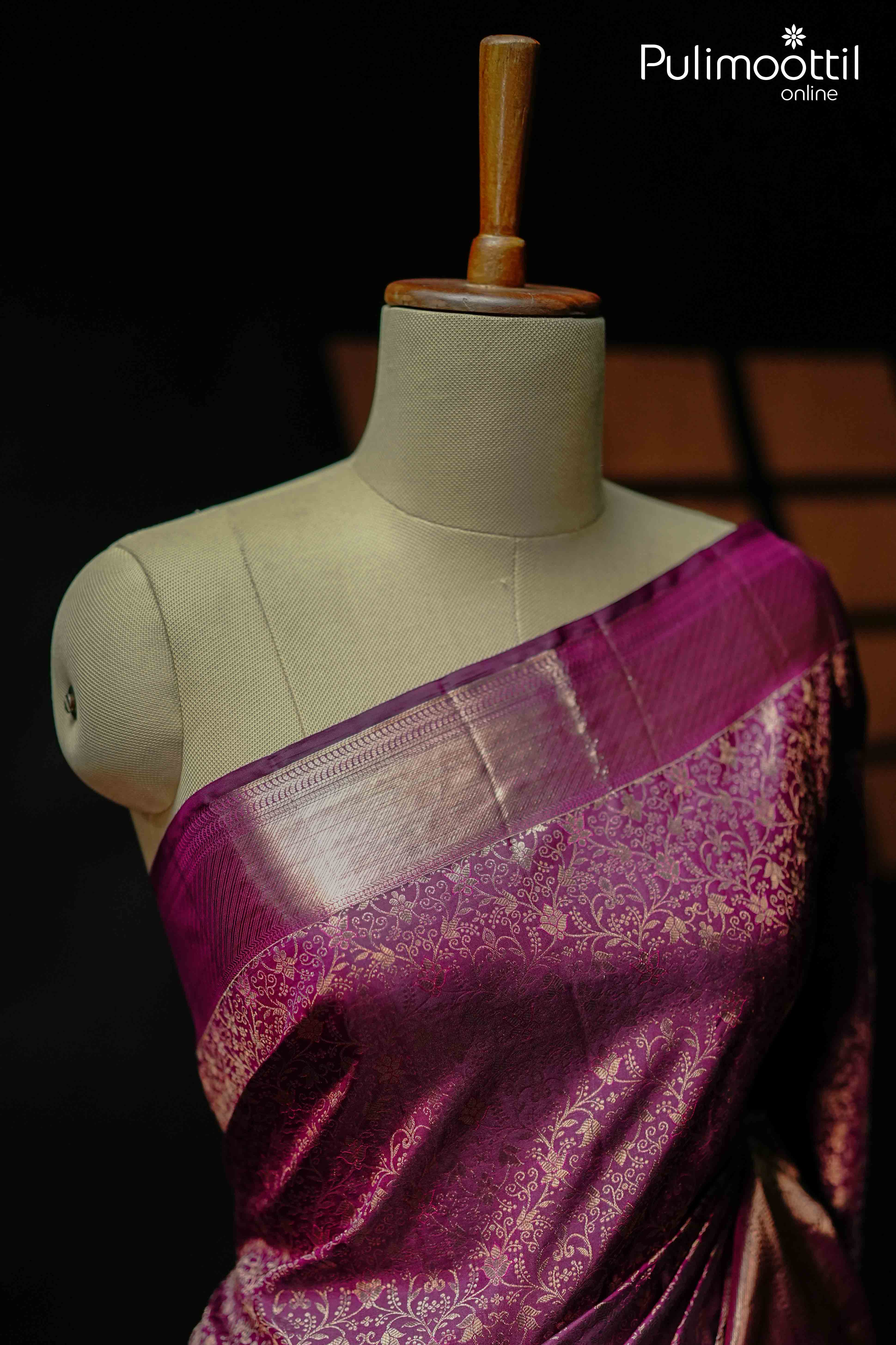 Purplle plum Kanchipuram wedding saree draped on a mannequin, featuring intricate copper zari floral motifs and a rich pallu — perfect for bridal and Onam occasions.