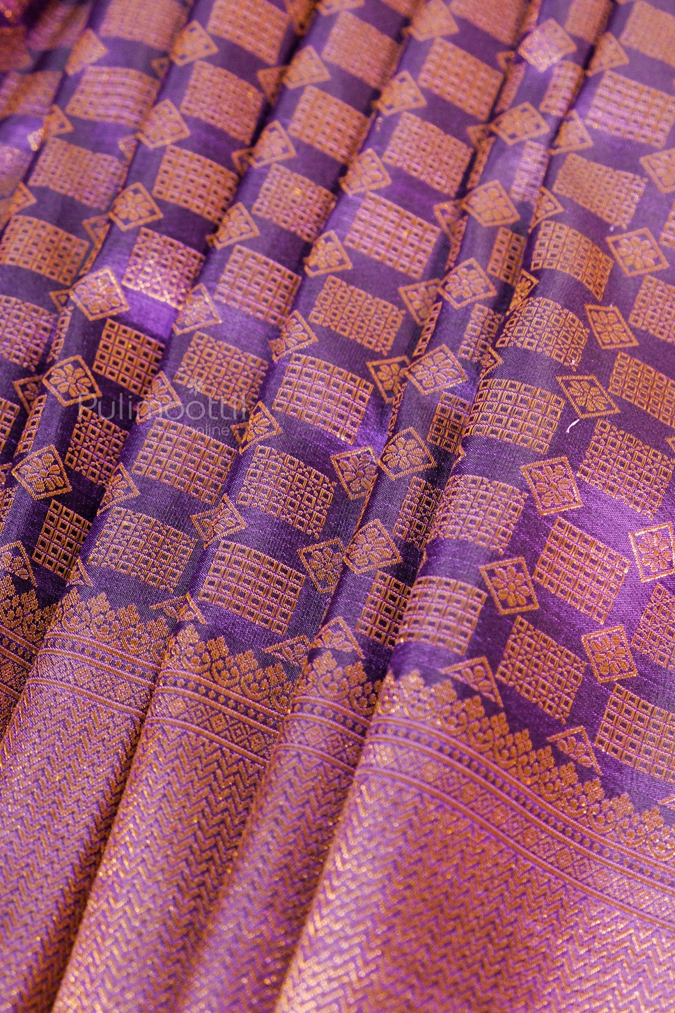Ripe plum Kanchipuram silk saree pleats featuring rich gold temple pattern