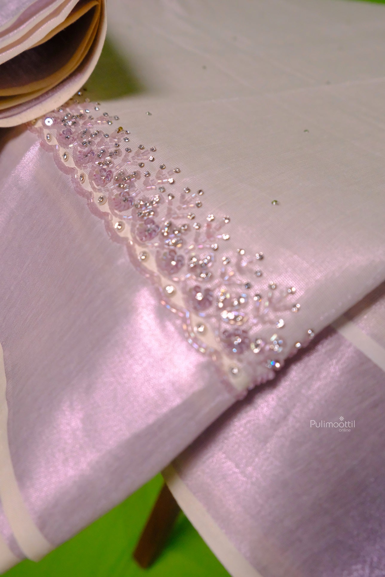 Close-up of rose gold Kerala tissue saree with intricate stone and bead embroidery on the border