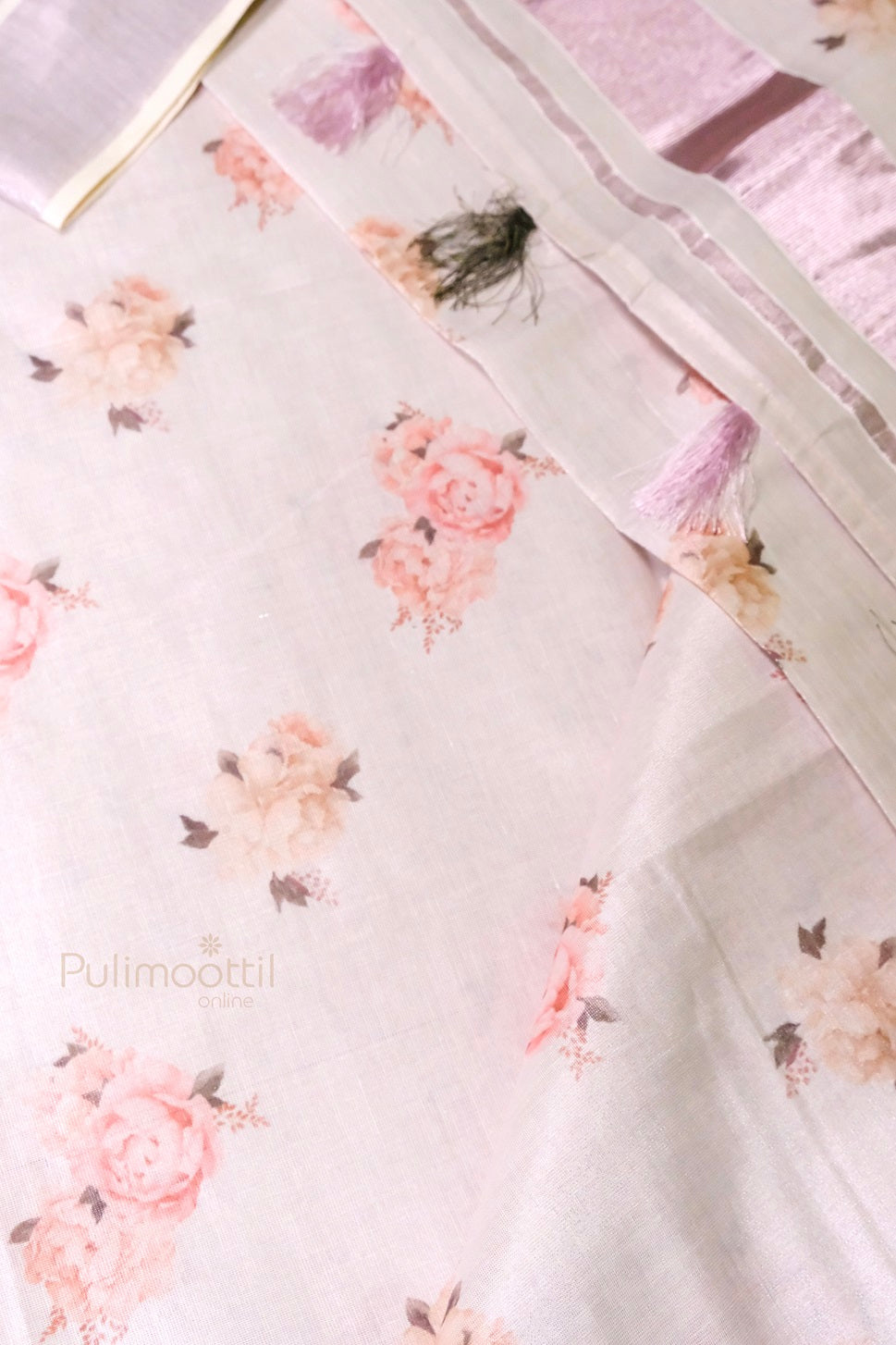 Detailed view of blouse piece of Kerala tissue saree border with metallic pink zari, cream stripes, and multicolored tassels with floral print