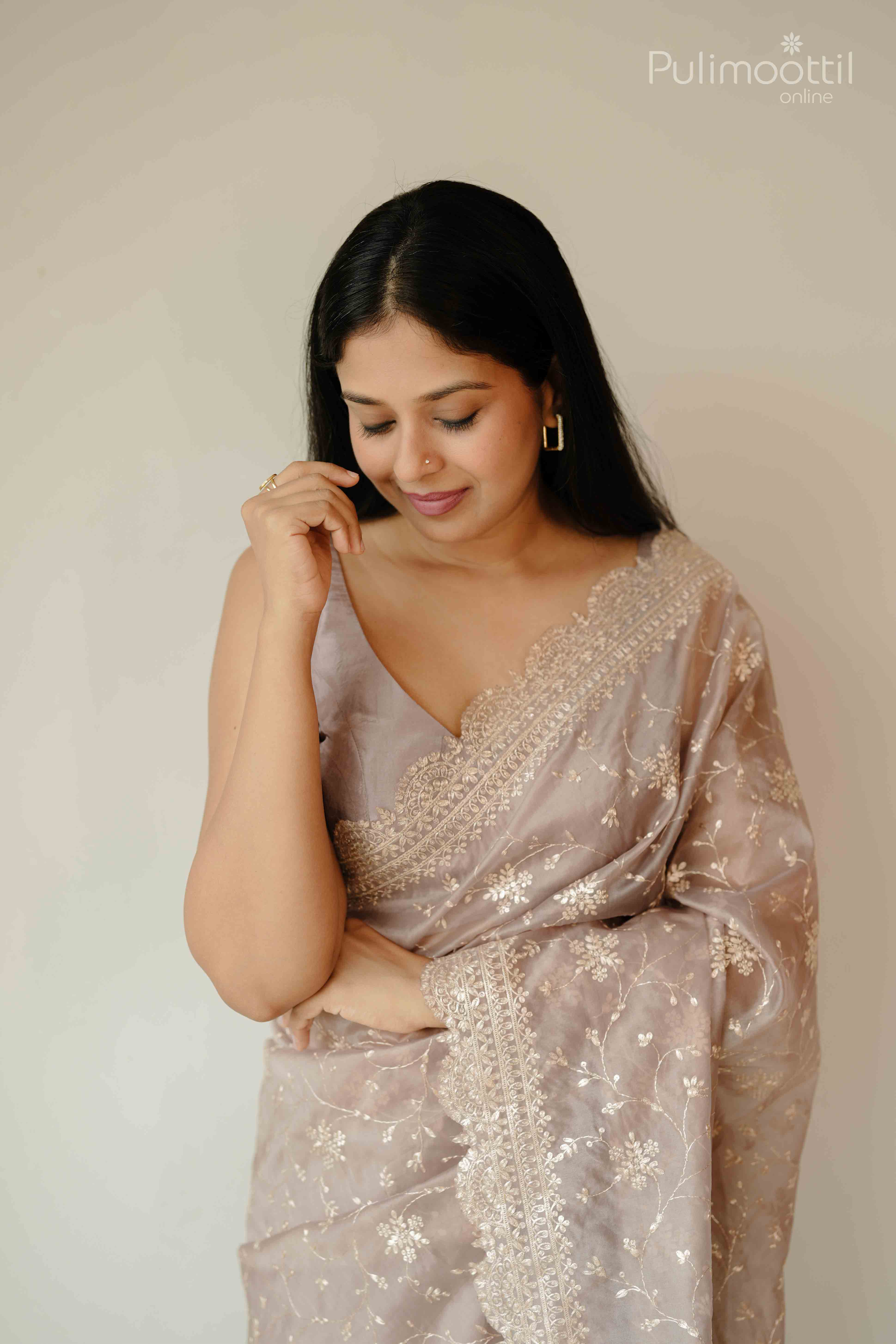 Close-up view of rosy brown designer saree with floral pitta embroidery and delicate scallop lace border.