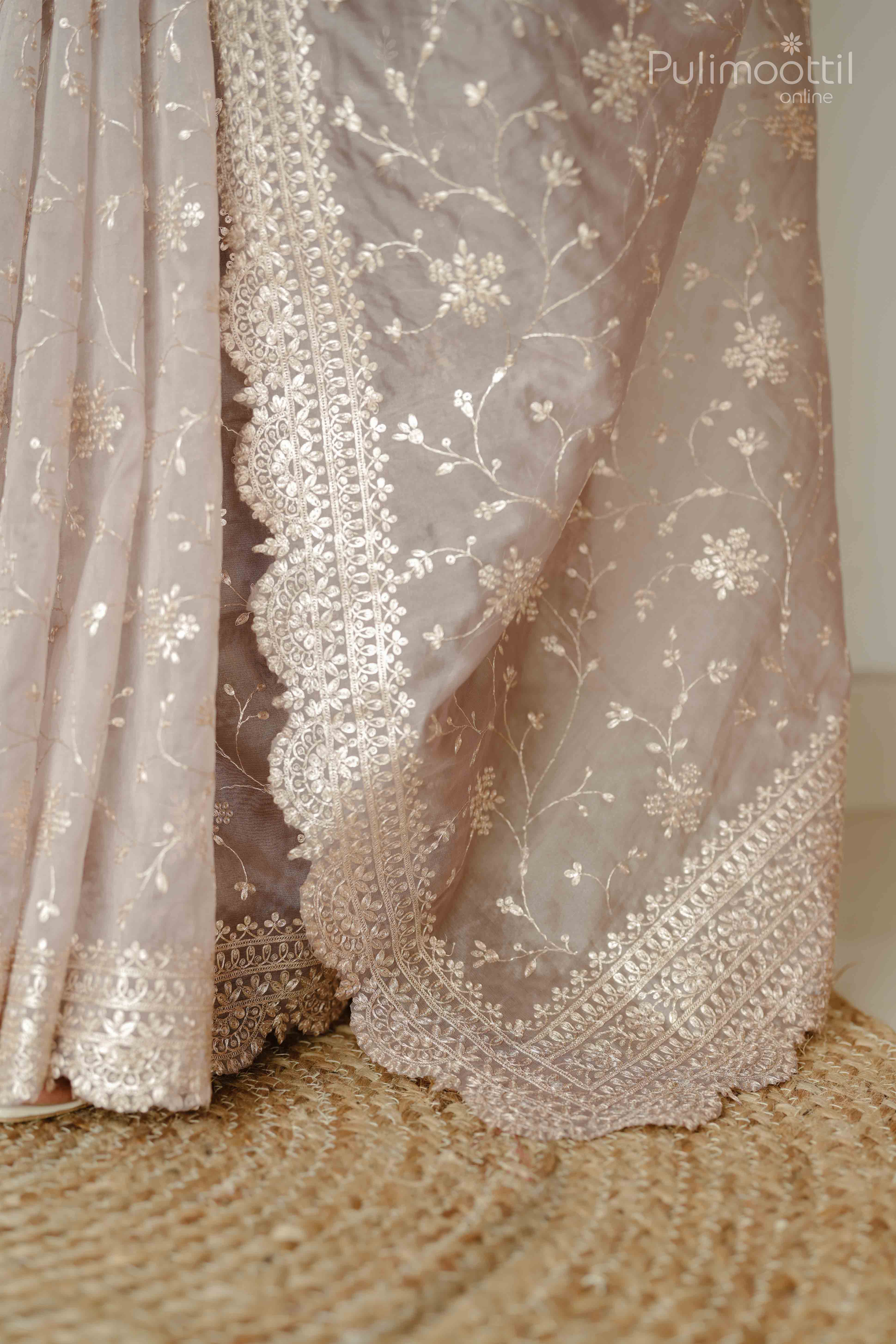 Lower half of organza saree showing intricate floral pitta embroidery and scalloped border design.
