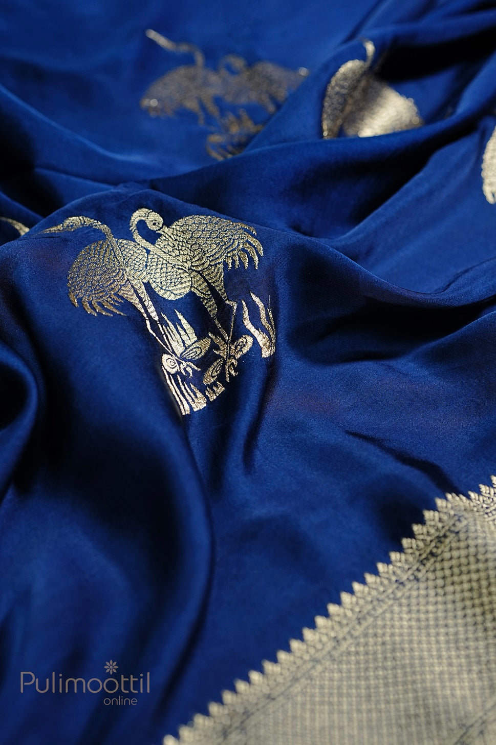 Close-up of royal blue Uppada silk saree with golden zari bird motifs and geometric pattern zari border, showcasing the intricate design and luxurious texture.