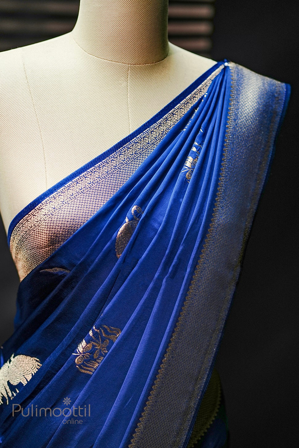Royal blue Uppada silk saree with golden zari bird motifs and geometric pattern zari border, draped elegantly on mannequin, showcasing the intricate design.