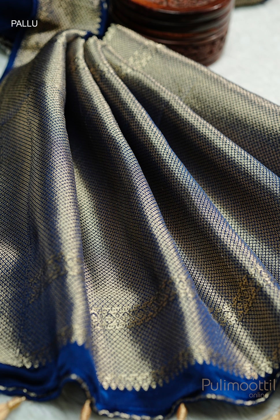Close-up of royal blue Uppada silk saree pallu with geometric pattern zari border and golden accents, showcasing the intricate craftsmanship.