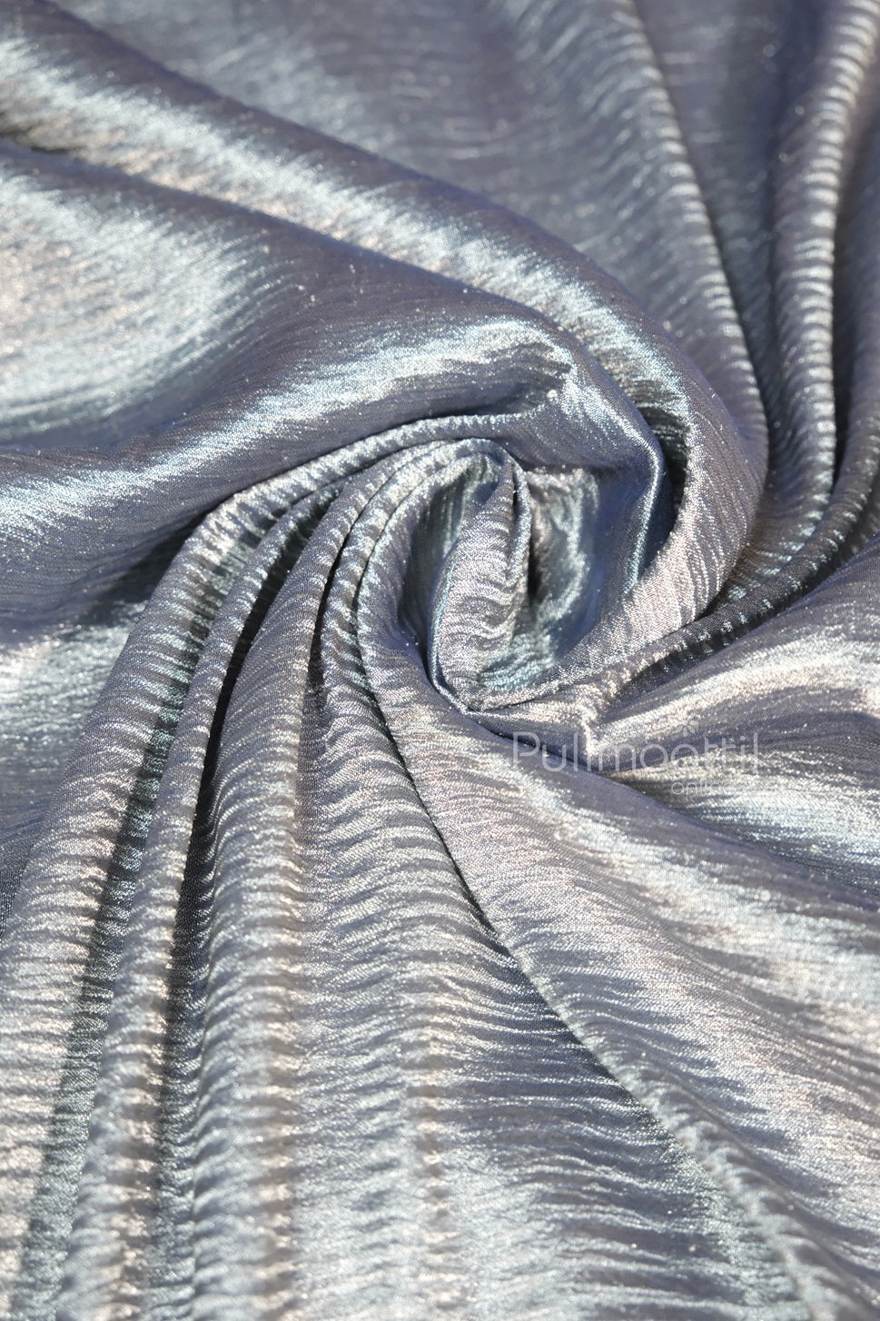 Crinkled grey‑blue silk blouse piece with glossy sheen, artfully draped in a swirl, Pulimoottil Online branded textile.