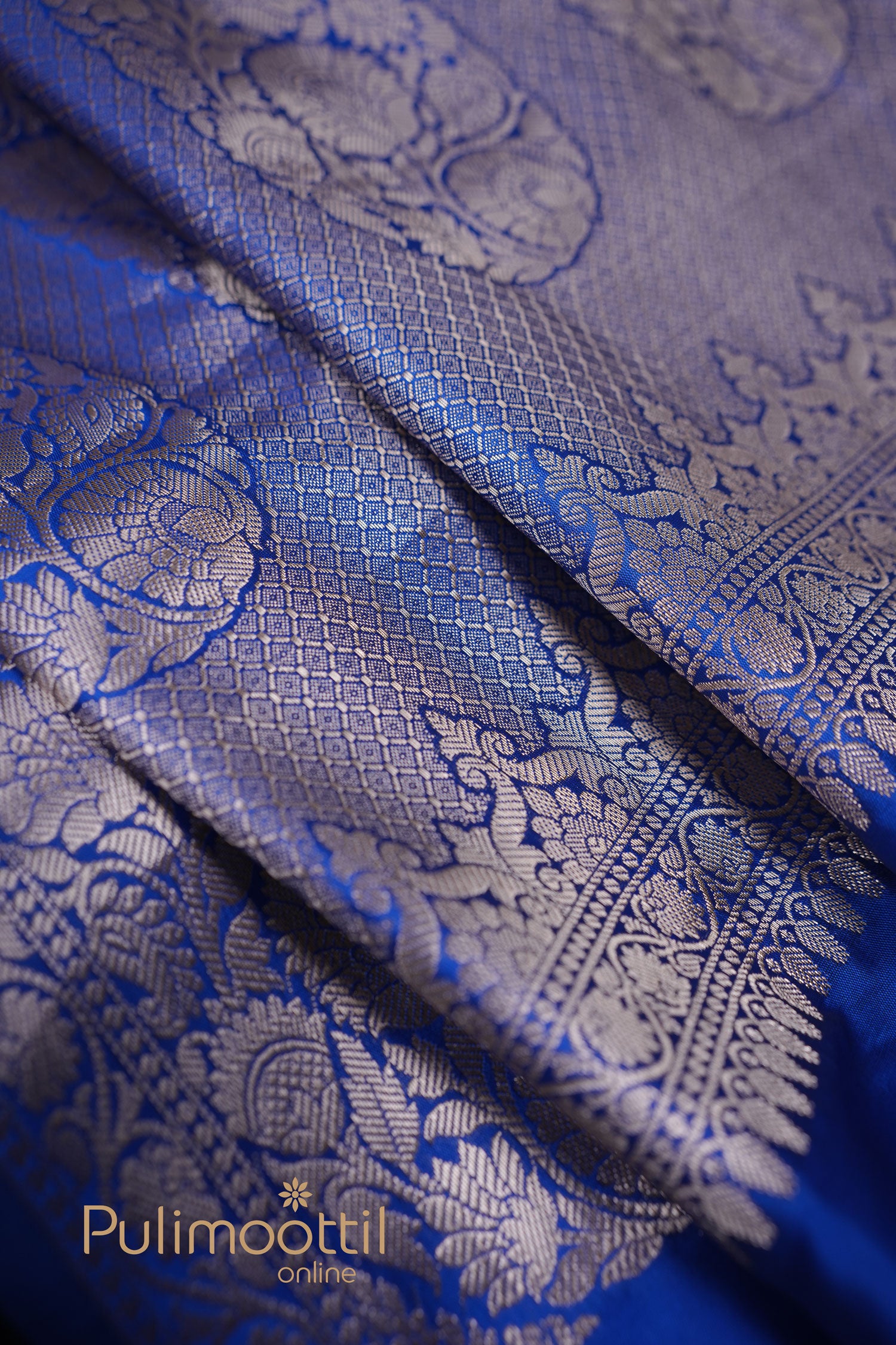 Detailed view of zari-woven pallu of royal blue semi silk saree with floral motifs.