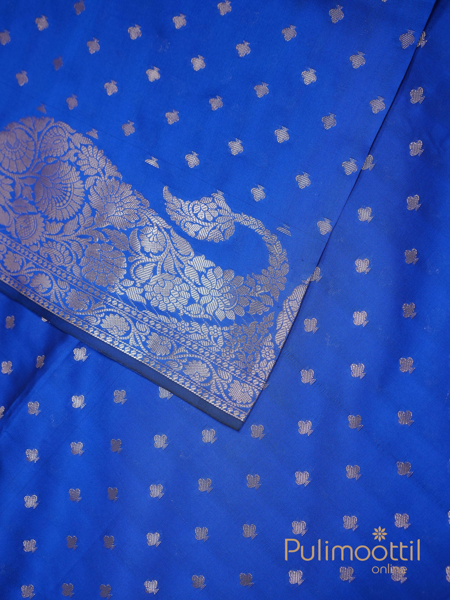 Flat lay of royal blue semi silk saree body with evenly spaced silver zari buttas.