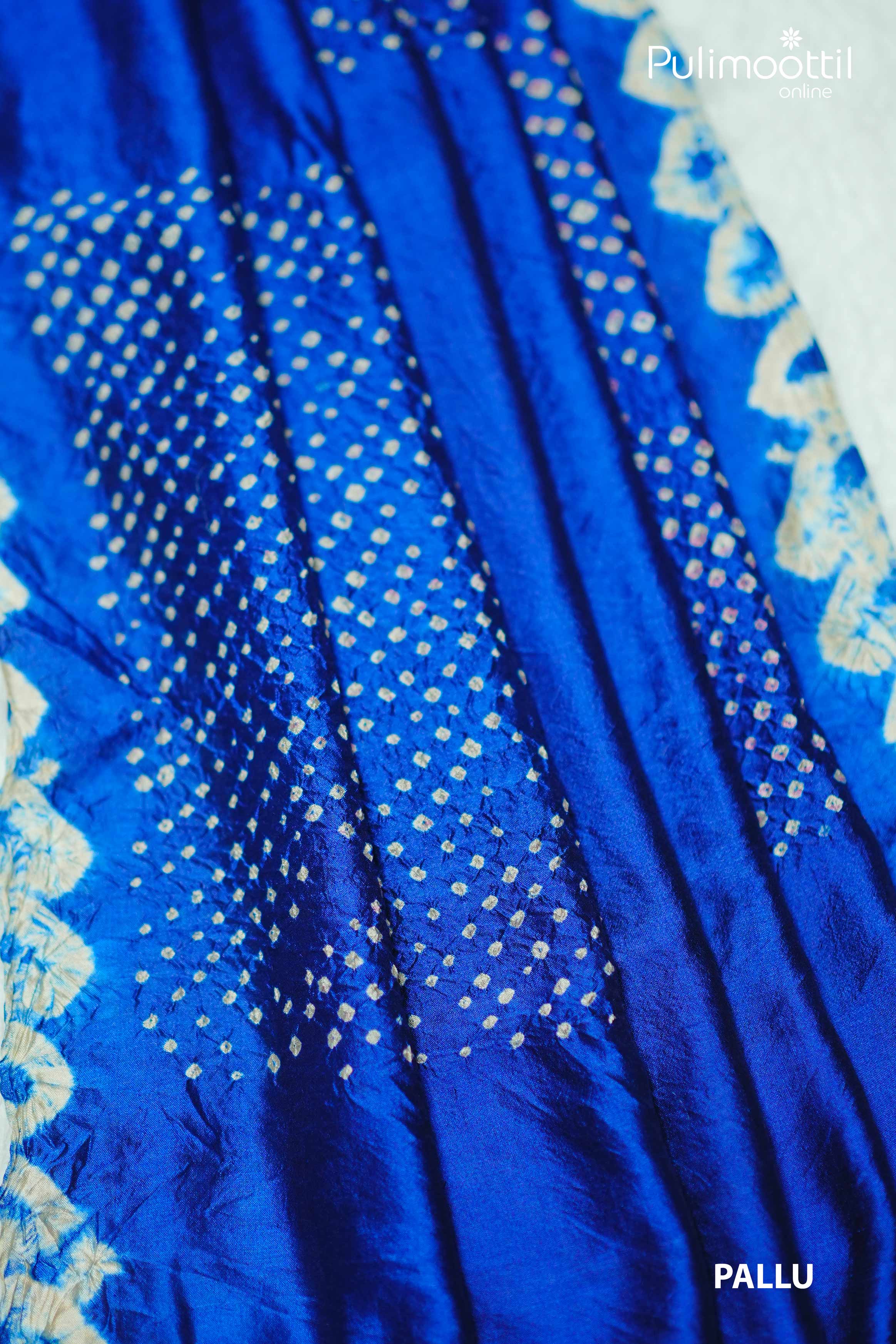 Close-up of the royal blue Tussar silk saree pallu showcasing white tie and dye patterns in a diagonal grid design with floral accents along the border.