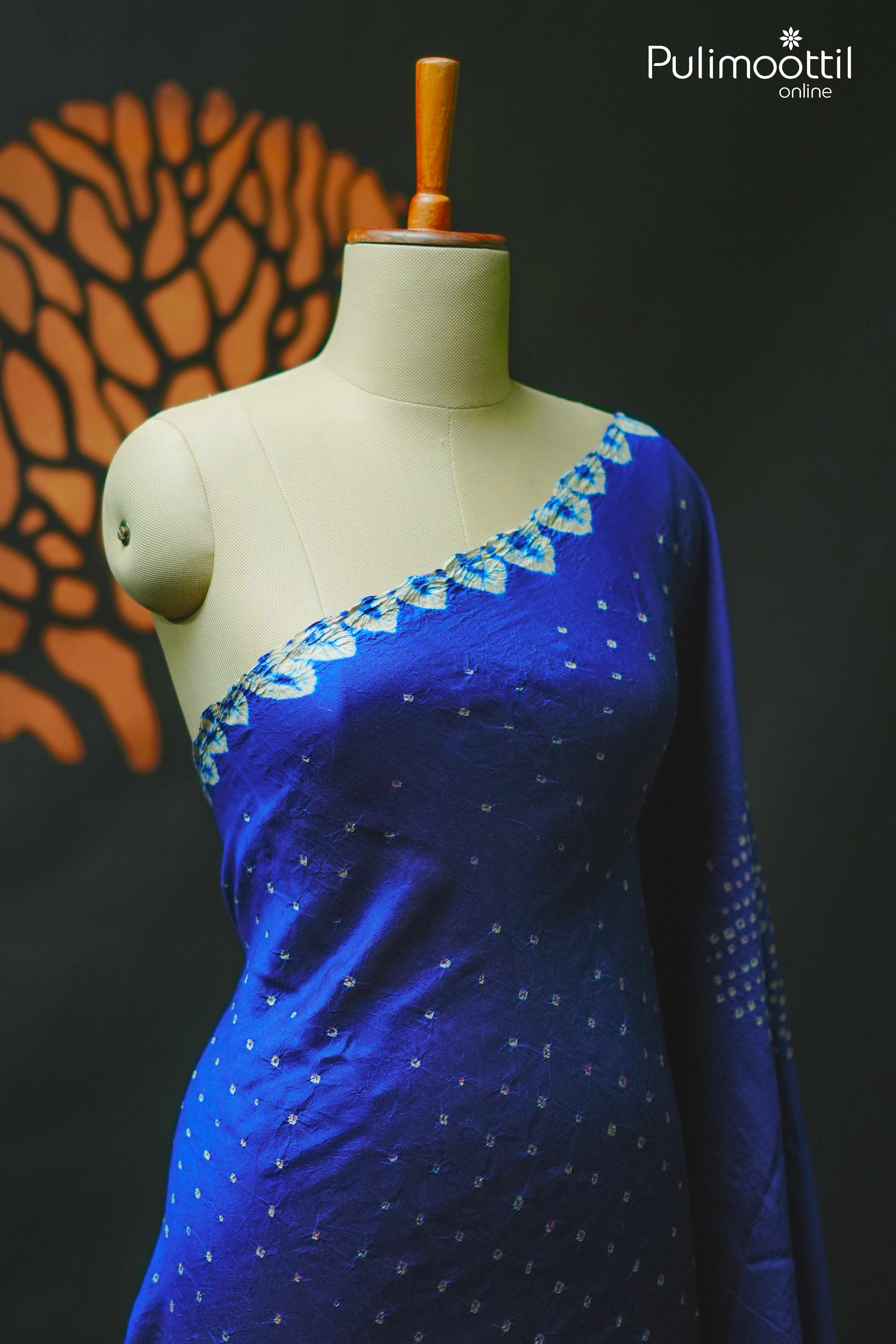Close-up of a royal blue Tussar silk saree displayed on a mannequin, highlighting the white tie and dye floral border along the neckline and delicate Chungidi-style motifs across the fabric.