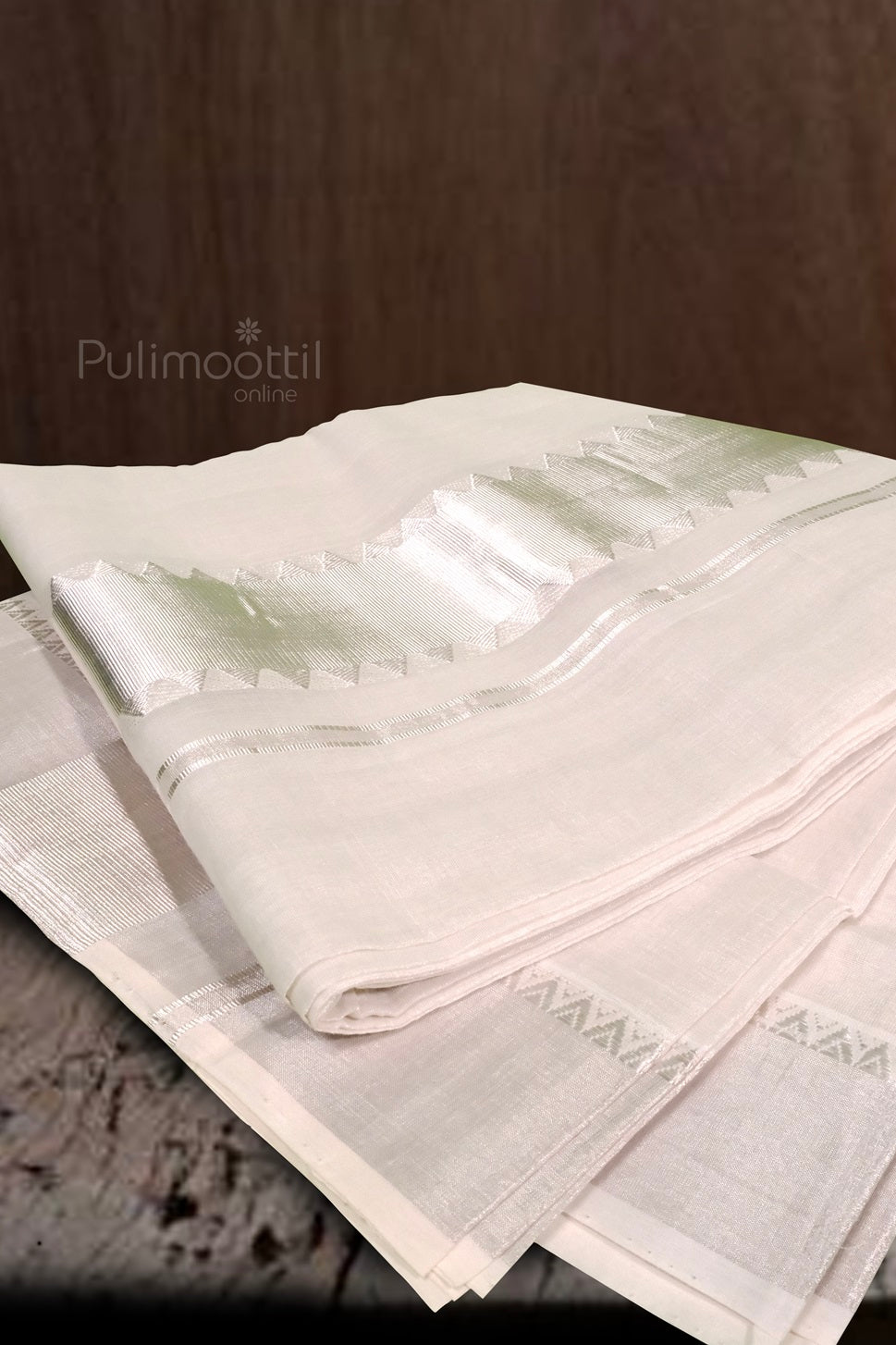 Folded Kerala traditional white cotton saree with silver kasavu border placed on wooden background