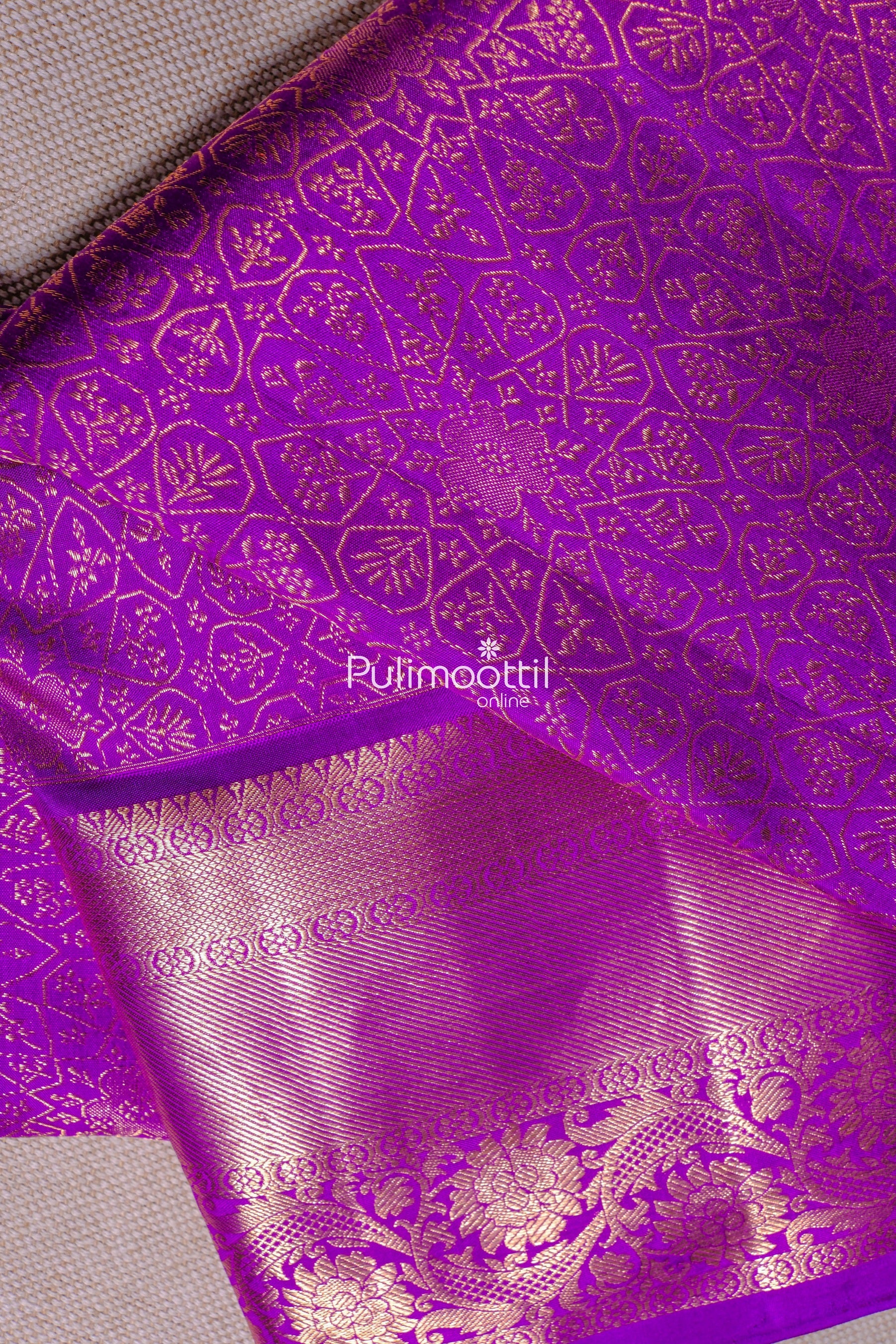 Close-up of a violet Kanchipuram saree with intricate golden floral and geometric patterns.