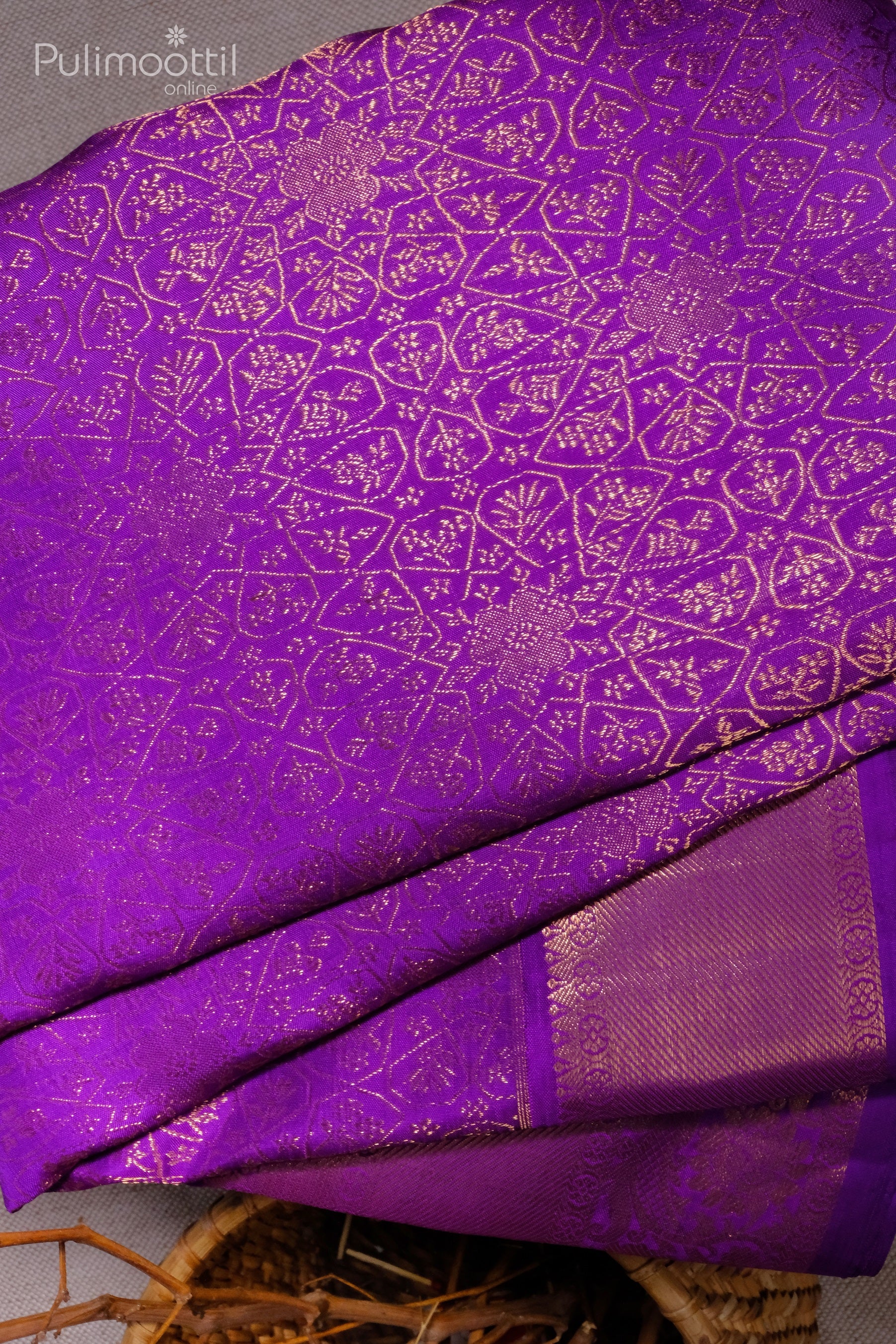 Violet Kanchipuram saree draped to display its elaborate golden floral and geometric woven design.