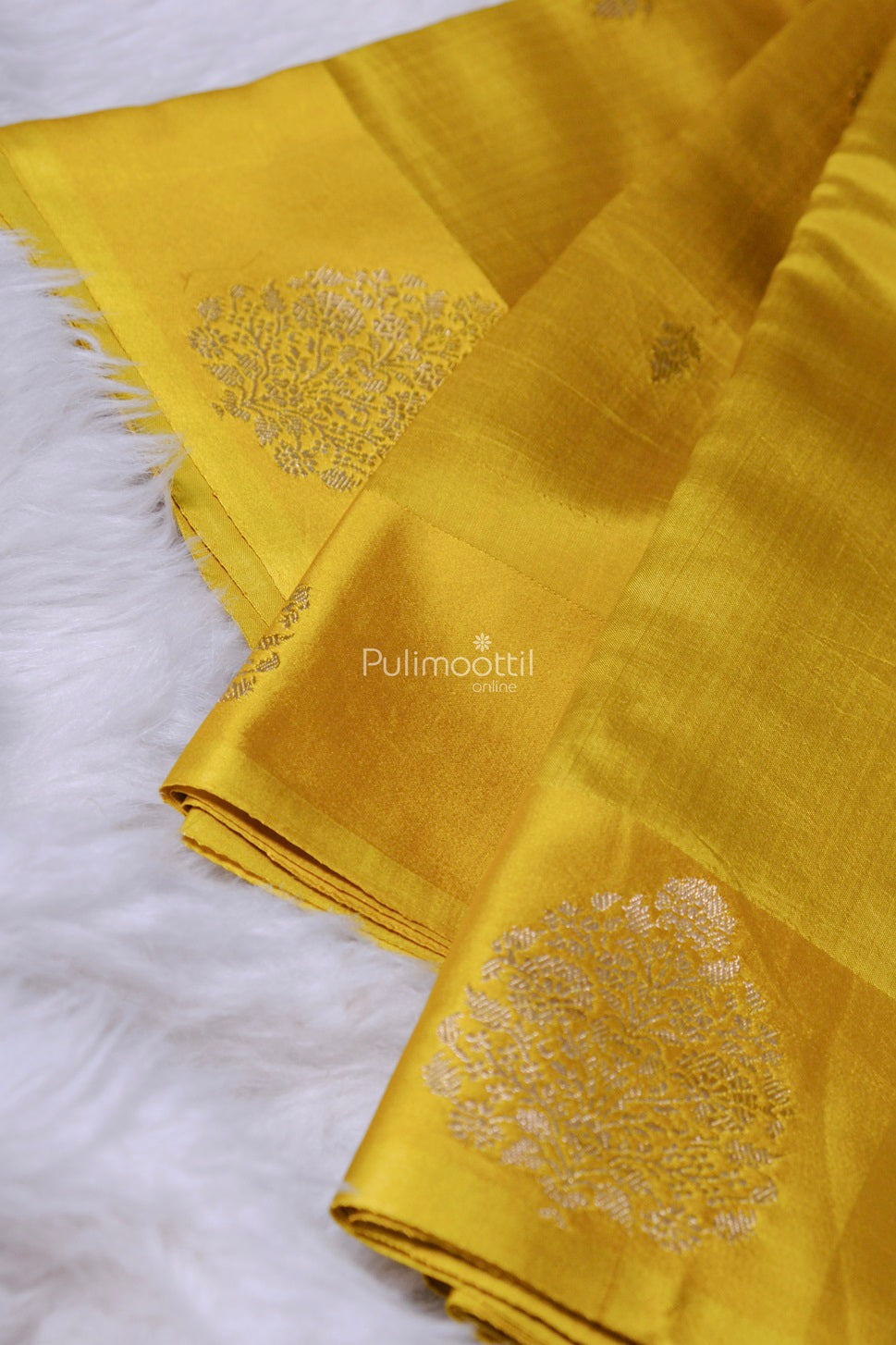 Traditional mustard yellow silk saree with intricate silver butta designs, neatly folded for display.