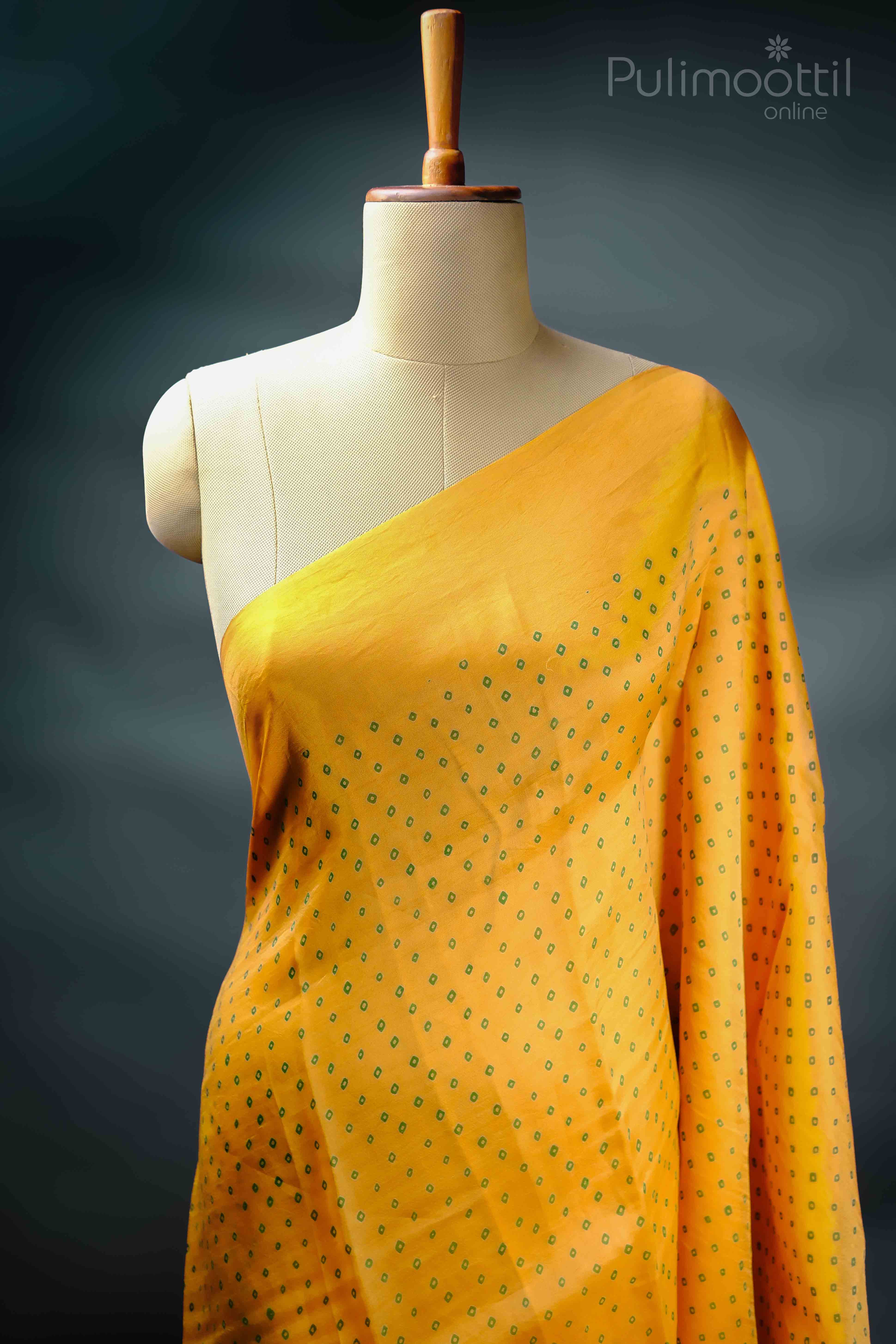 Yellow saree with a subtle pattern of green diamond-shaped prints, displayed on a mannequin.