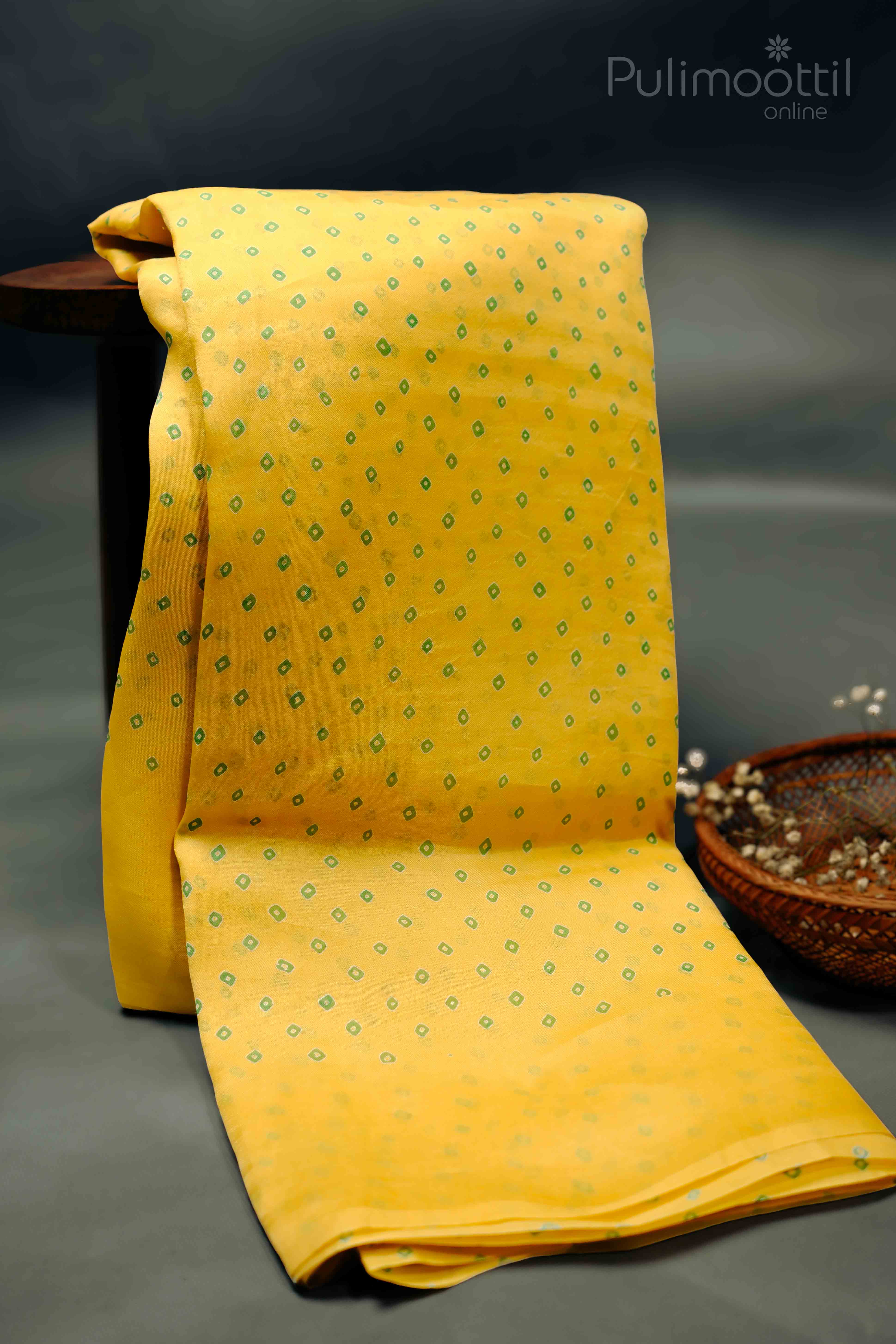 Yellow saree with green diamond-shaped prints, neatly draped on a flat surface.