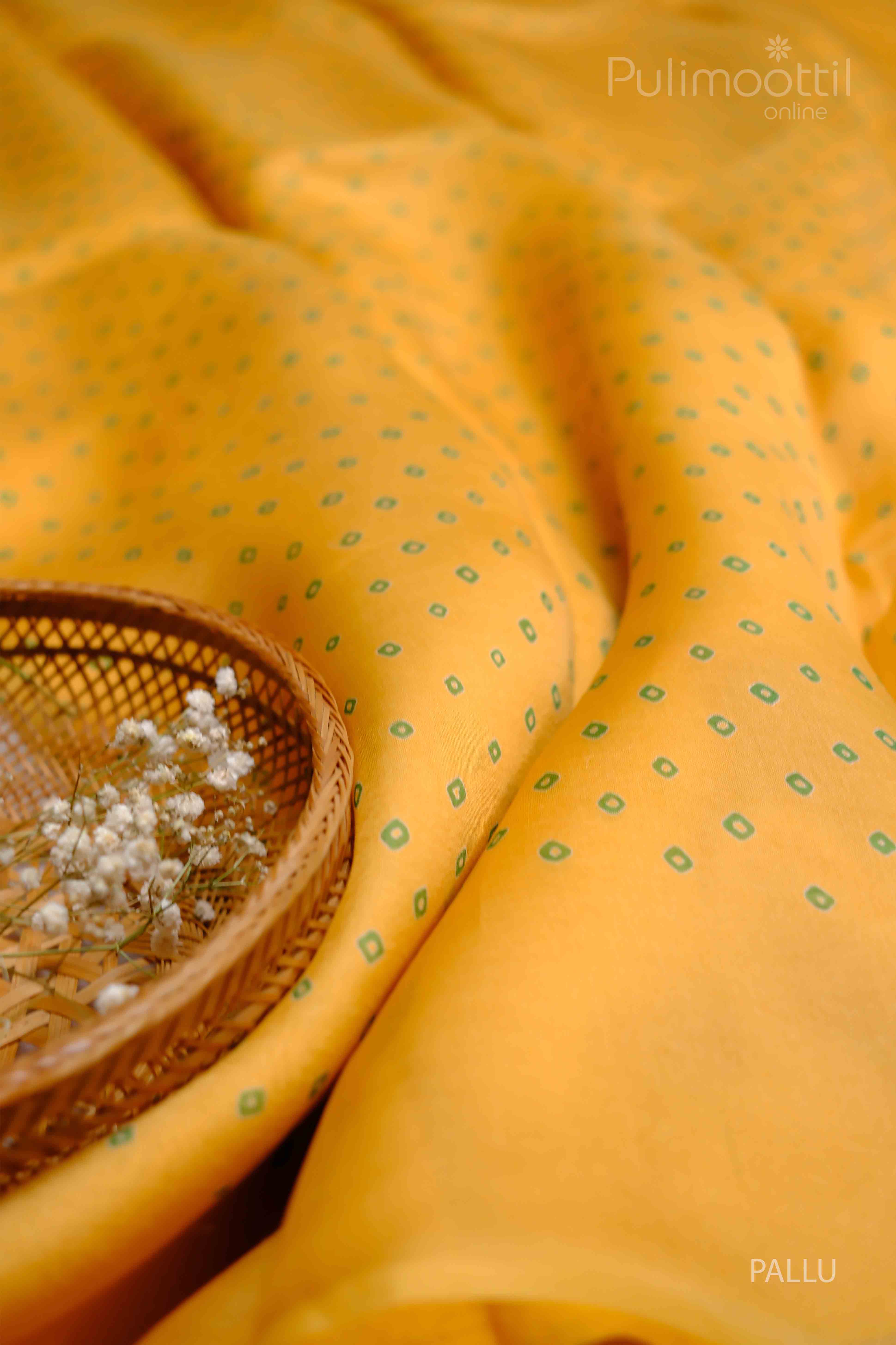 Close-up of the yellow saree with green diamond prints, showcasing the fabric texture and design.