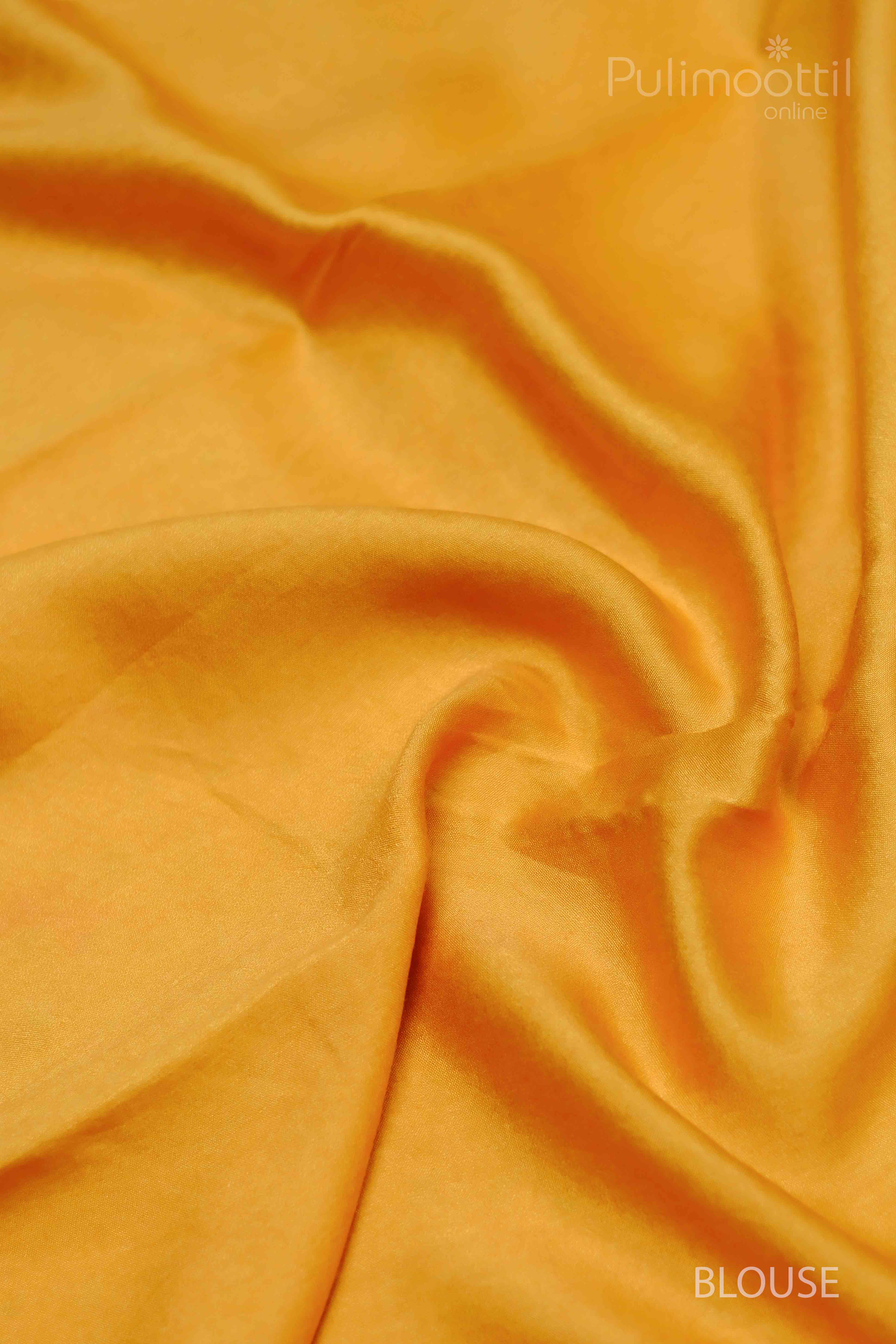Yellow saree with green prints, highlighting the pallu area with smooth, flowing fabric.