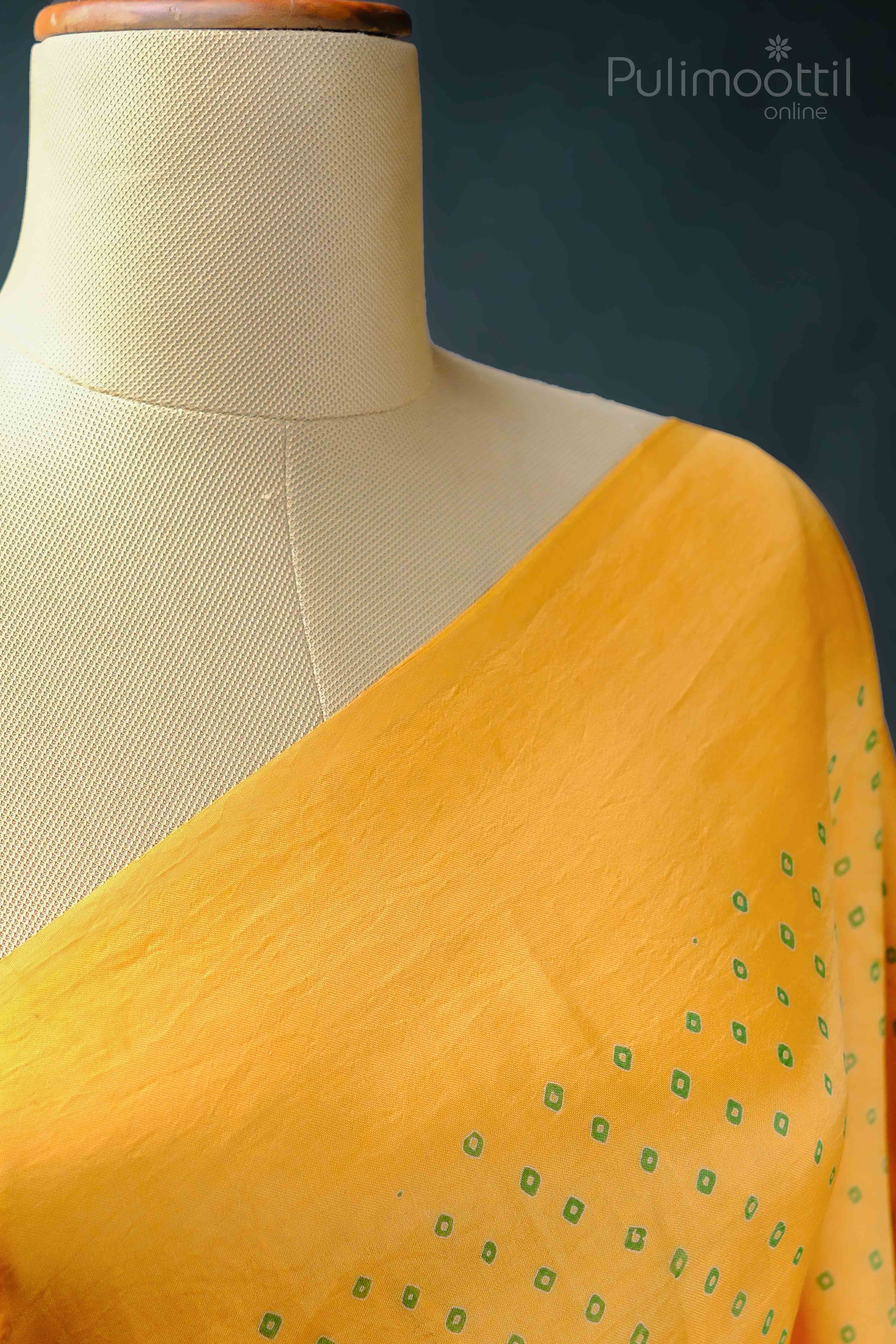 Close-up of yellow fabric with a smooth texture, intended for the blouse portion of the saree.