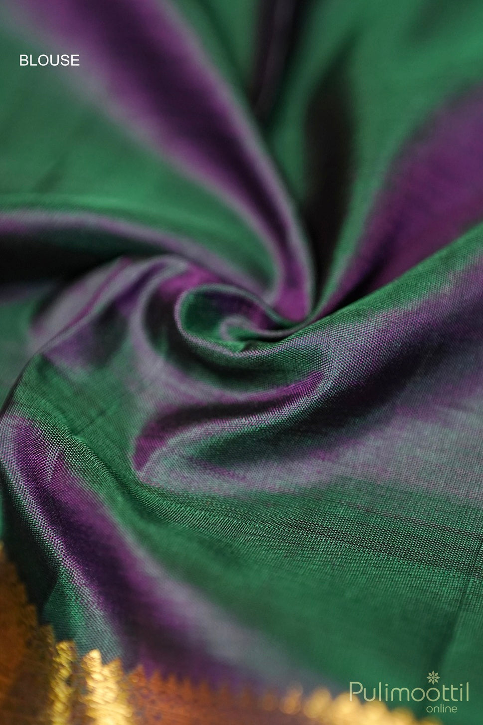 Close-up of a green and purple silk blouse fabric with a soft texture, featuring a golden zari border, elegantly folded in a swirl pattern."