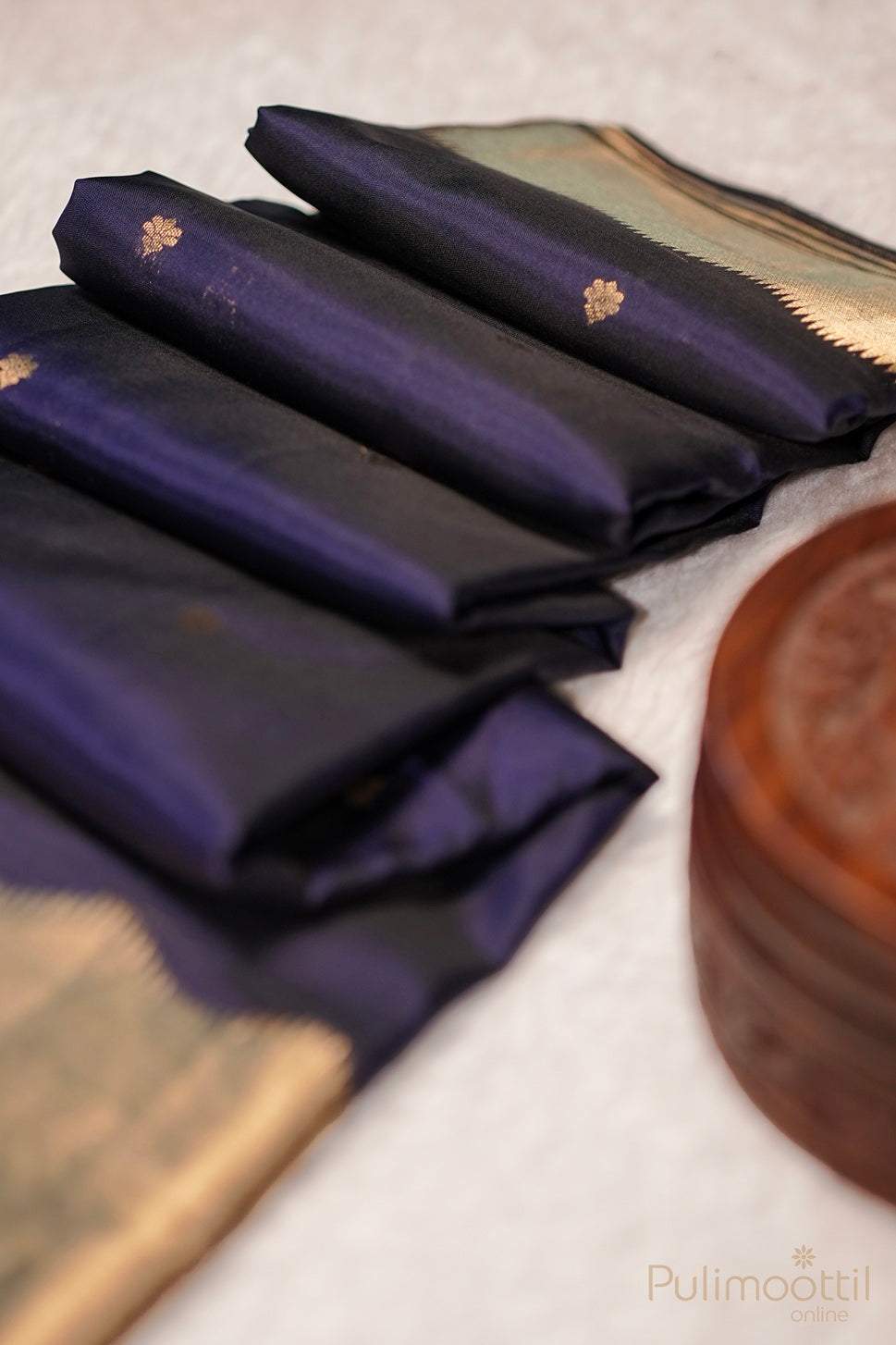 Close-up of designer golden pallu with intricate patterns on dark blue Kanchipuram silk saree.