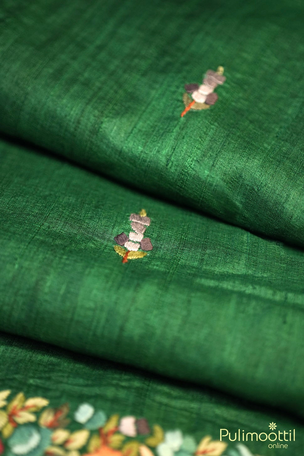 Folded bottle green jute silk saree with hand embroidered floral buttas and border.
