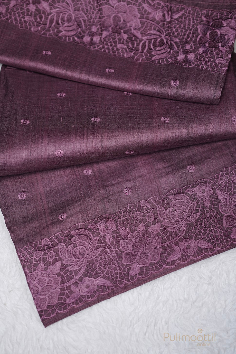 Full view of a purple saree laid out, highlighting the floral lace borders and small embroidered patterns.