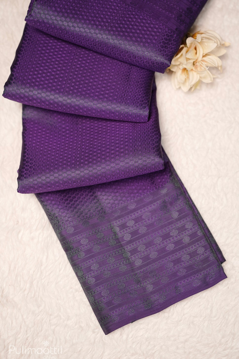 Violet Kanchipuram self print saree partially unfolded, highlighting the border and body design.