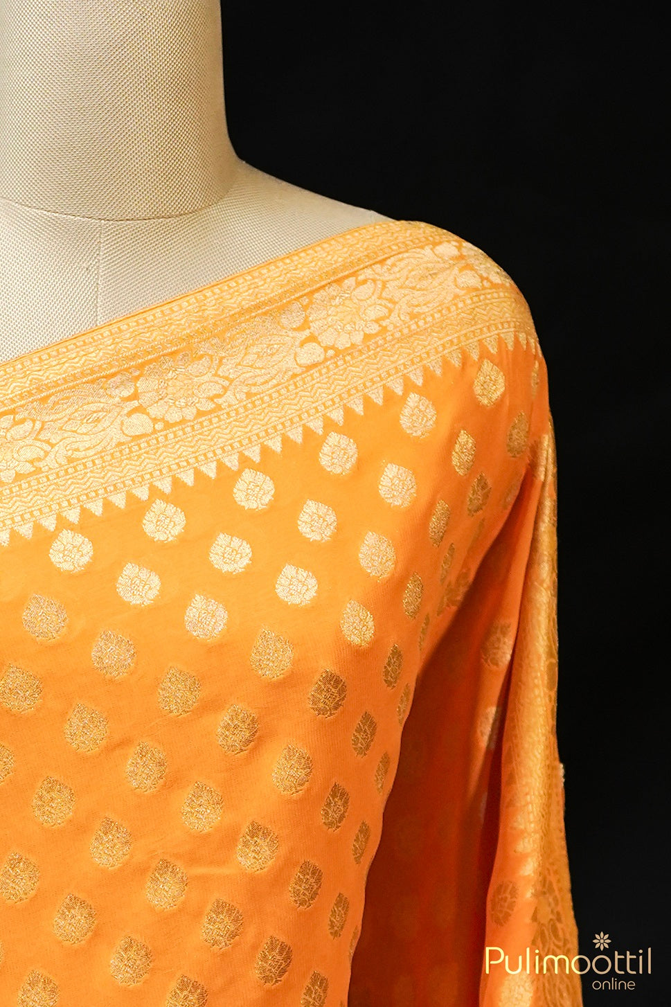 Mustard yellow Banarasi saree with golden buttas and border, draped on mannequin.