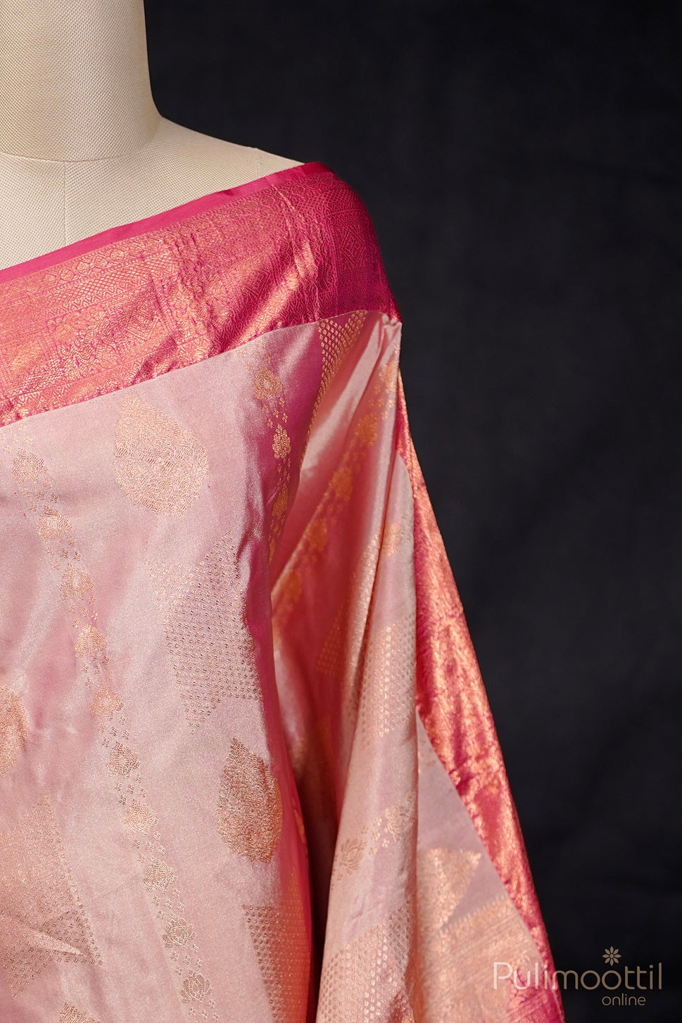 Melon colour semi Kanchipuram saree draped on mannequin highlighting designer body and contrast border.
