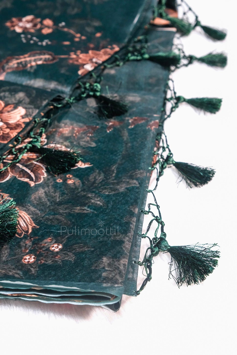 Pallu end of the dark green saree with green tassel detailing and floral print.
