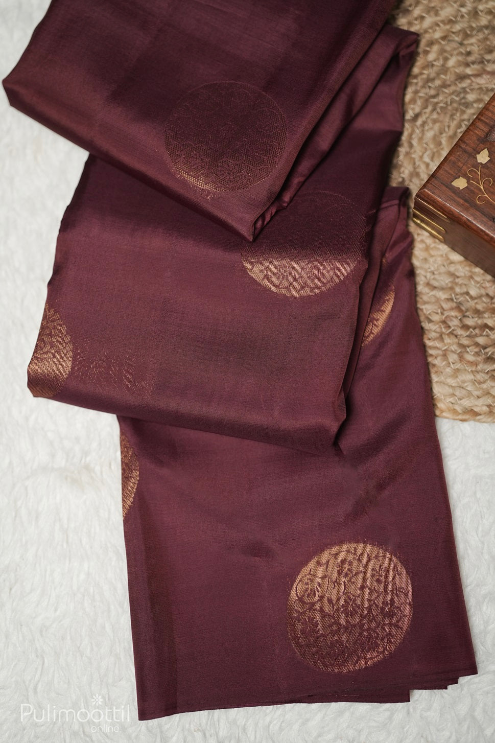 Close-up of copper round buttas on terracotta Kanchipuram saree fabric