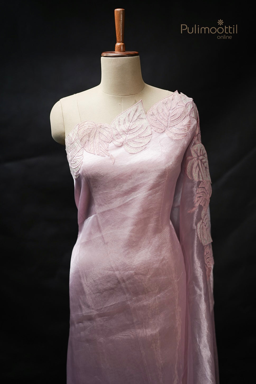 Light rose organza saree draped on mannequin featuring plain body with applique work border on one side, perfect for wedding and bridal sarees by Pulimoottil Silks Thrissur.