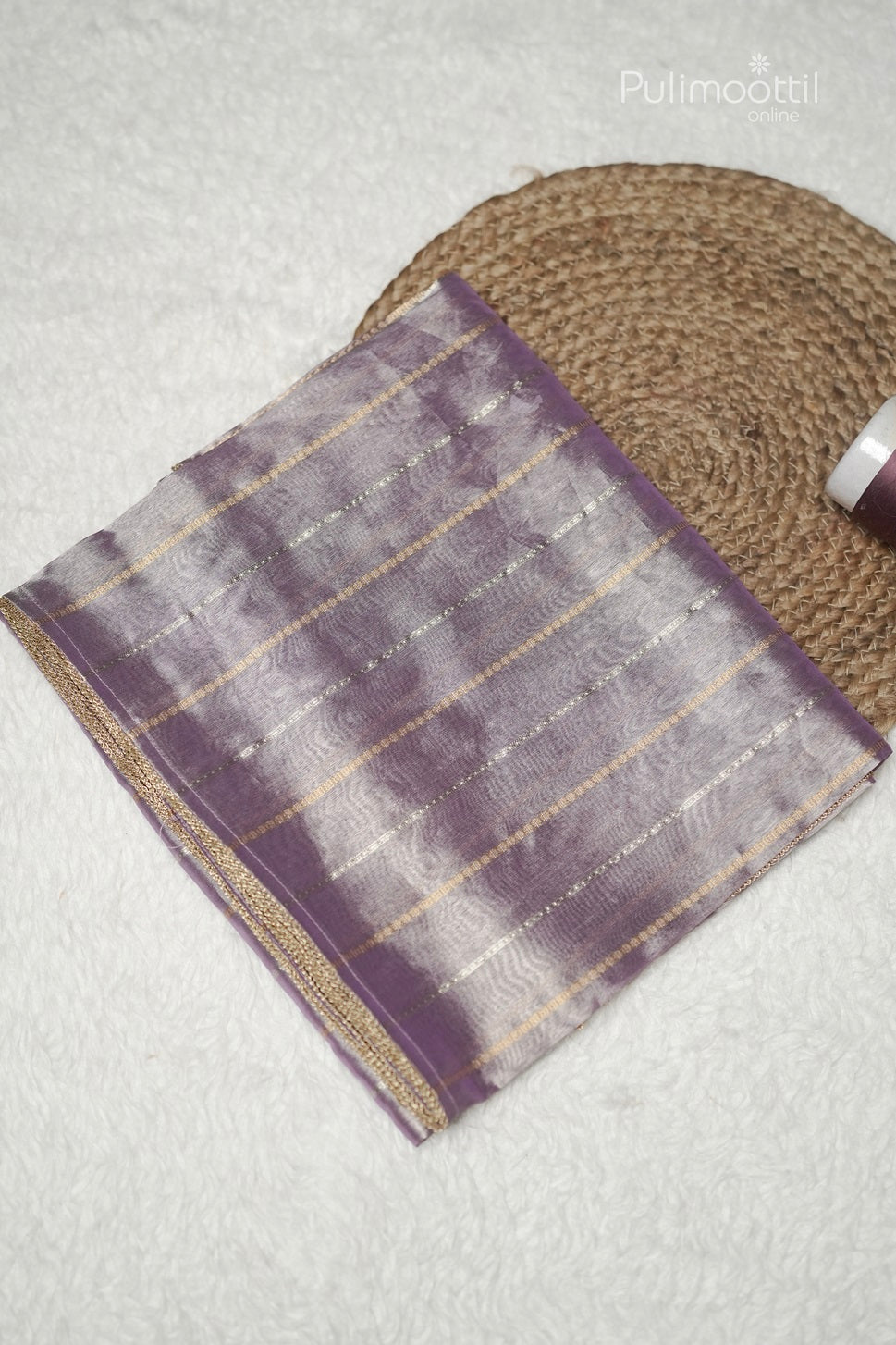 Folded lavender organza saree showing golden silver stripes and lace border