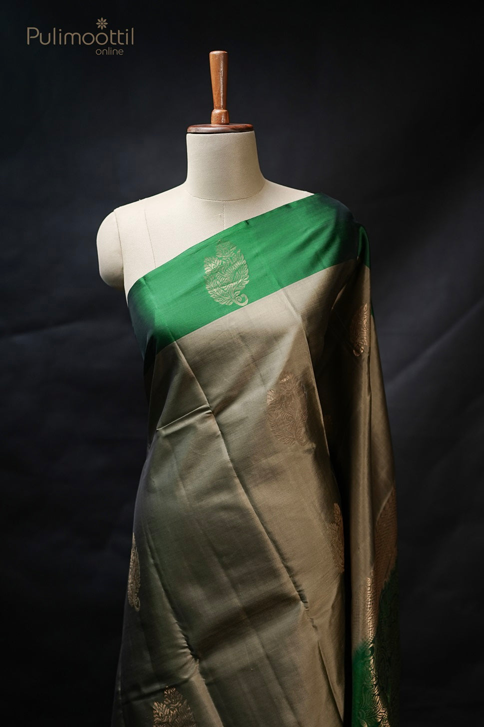 Pastel olive green Kanchipuram soft silk saree draped on mannequin with golden buttas and contrasting green border, elegant traditional wedding and bridal saree from Thrissur Pulimoottil Silks.
