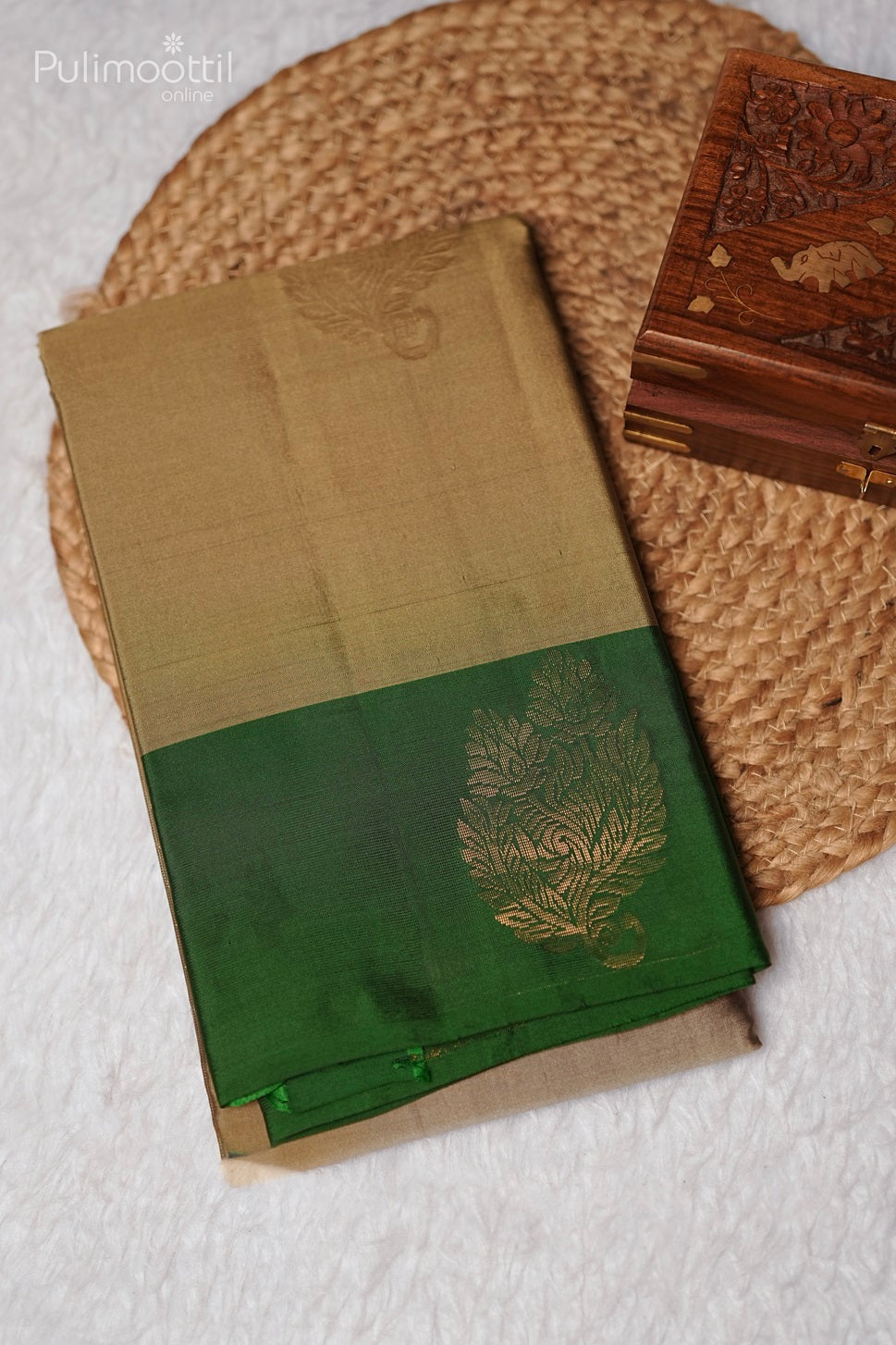 Folded pastel olive green Kanchipuram soft silk saree with golden buttas and contrasting green border, ideal for festive, wedding, and bridal occasions from Thrissur Pulimoottil Silks.