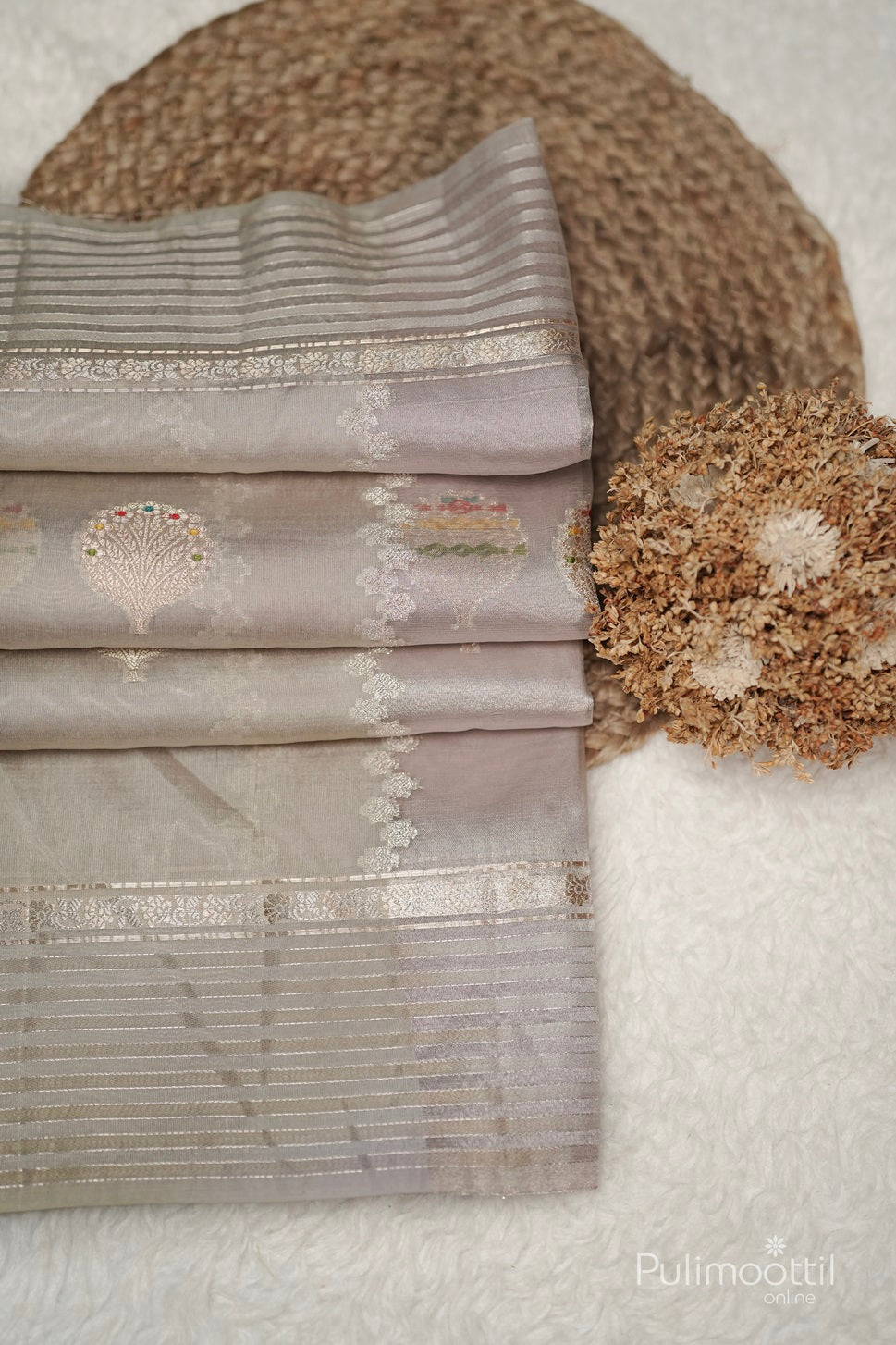 Close-up of ivory Banarasi silk saree on mannequin, showing golden and multithread motifs with red border, suitable for wedding saree or party wear.