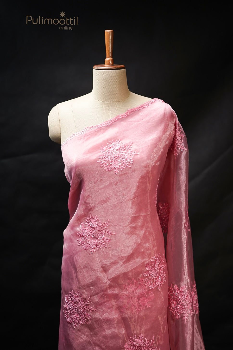 Light deep pink organza fancy saree draped on mannequin with delicate thread and sequins embroidery and scallop border, perfect for wedding and bridal sarees from Thrissur Pulimoottil Silks.
