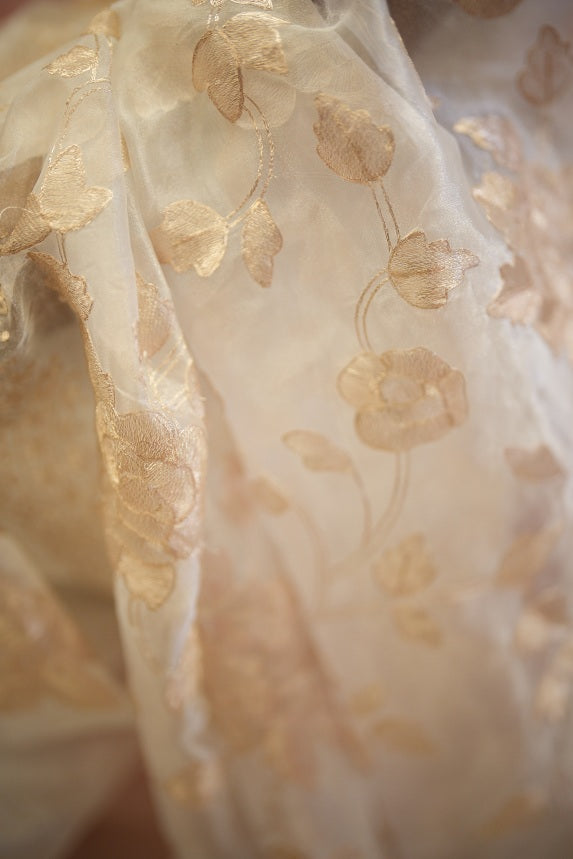 Close-up of white organza saree with intricate golden pitta floral design and translucent texture