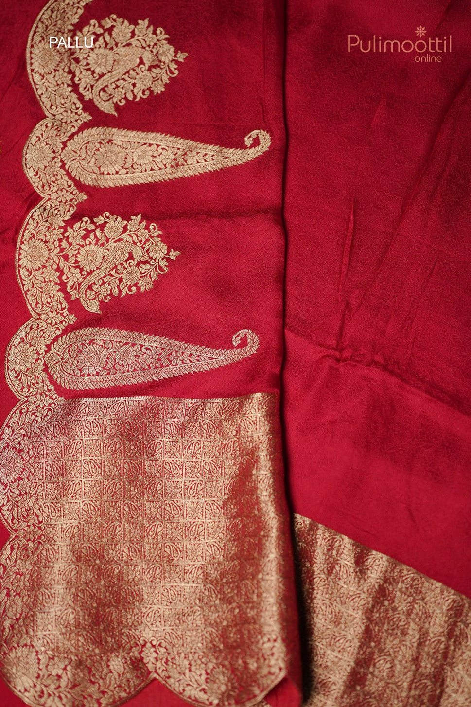 Folded chili red Banarasi silk saree with golden mango motif border and intricate pallu