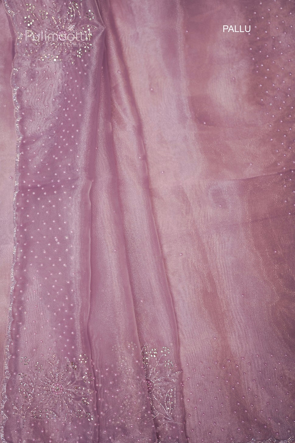 Folded lavender organza saree with bead embellishments and a scallop border, highlighting its luxurious design.
