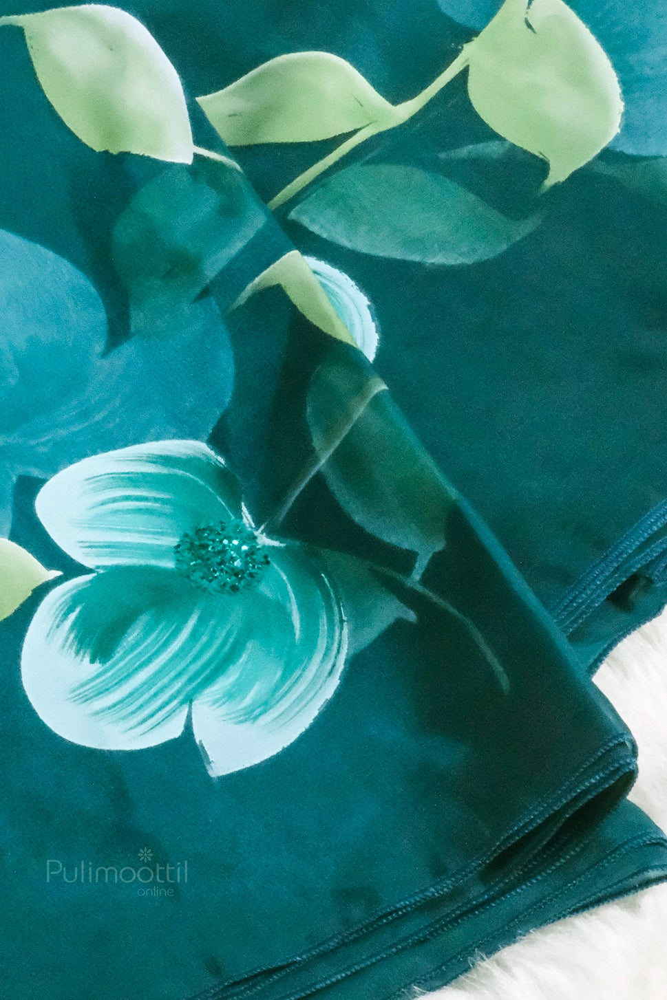 Close-up of hand-painted green floral motif on peacock blue organza fabric