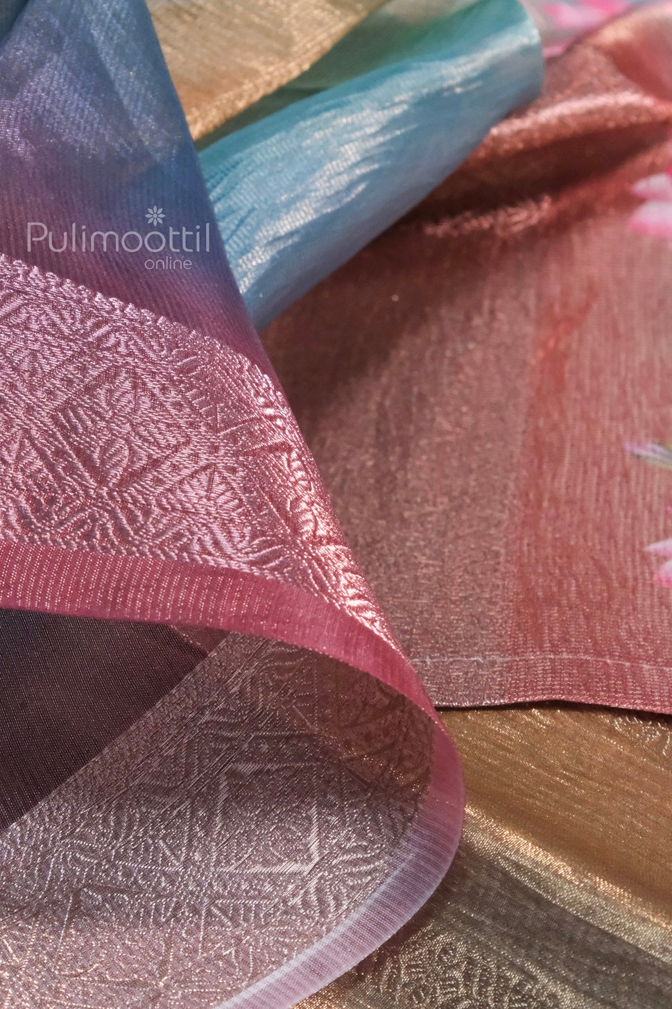Close-up of crushed organza tissue saree in pink and blue hues with intricate woven patterns.
